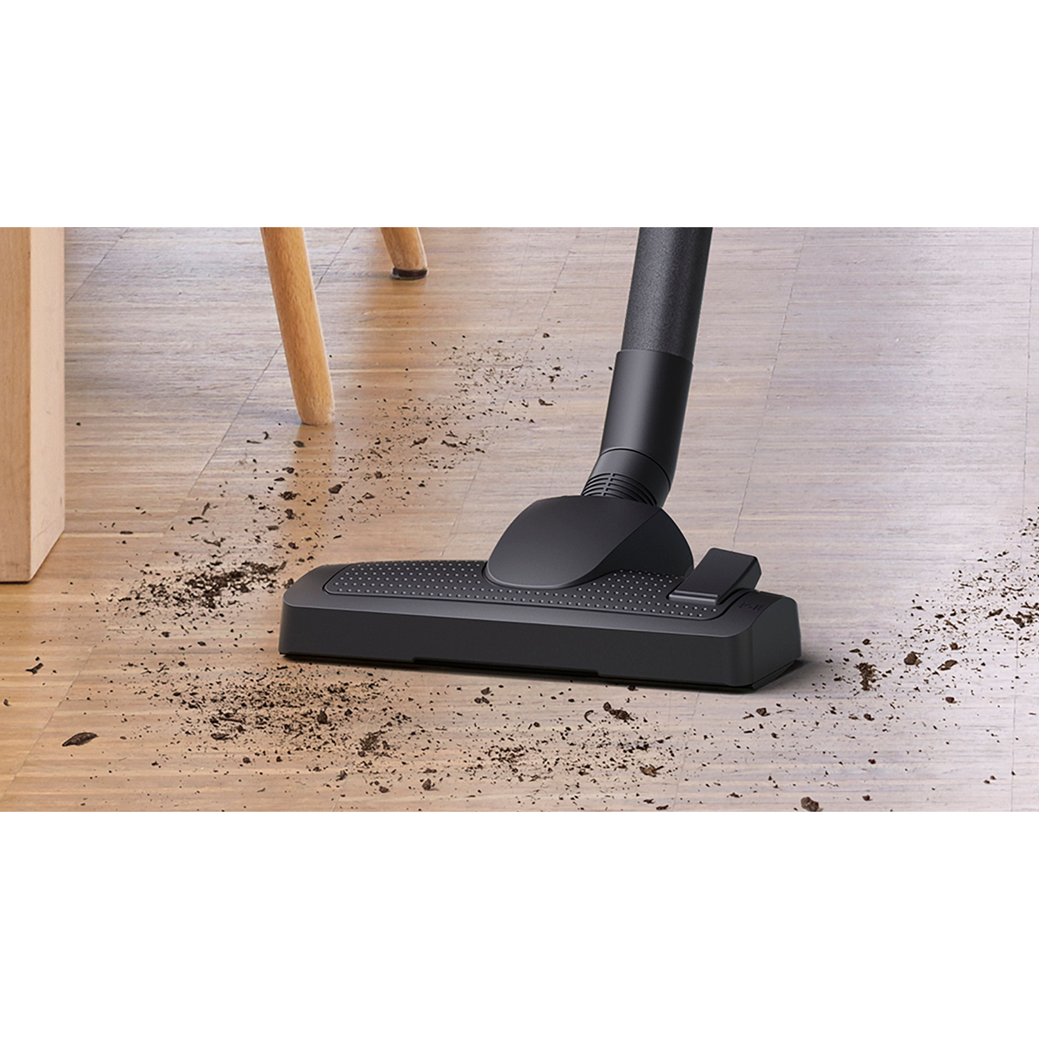 Vacuum cleaner head on dirty floor with dirt and debris.