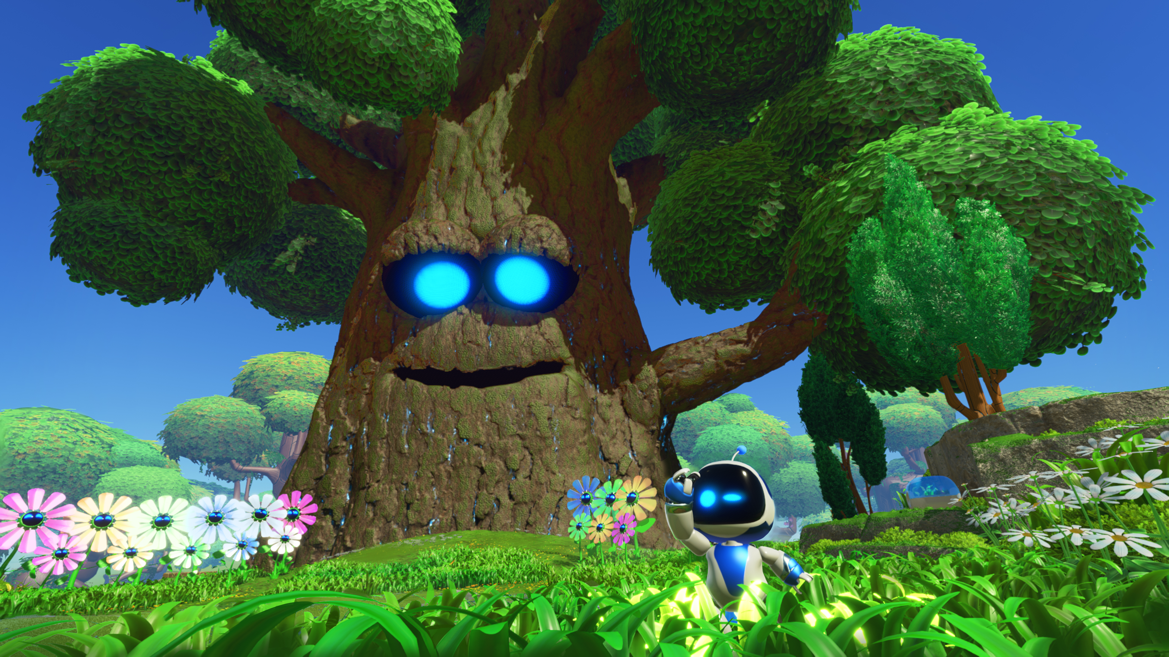 Astro Bot steht in einer farbenfrohen, cartoonartigen Umgebung neben einem Baum.