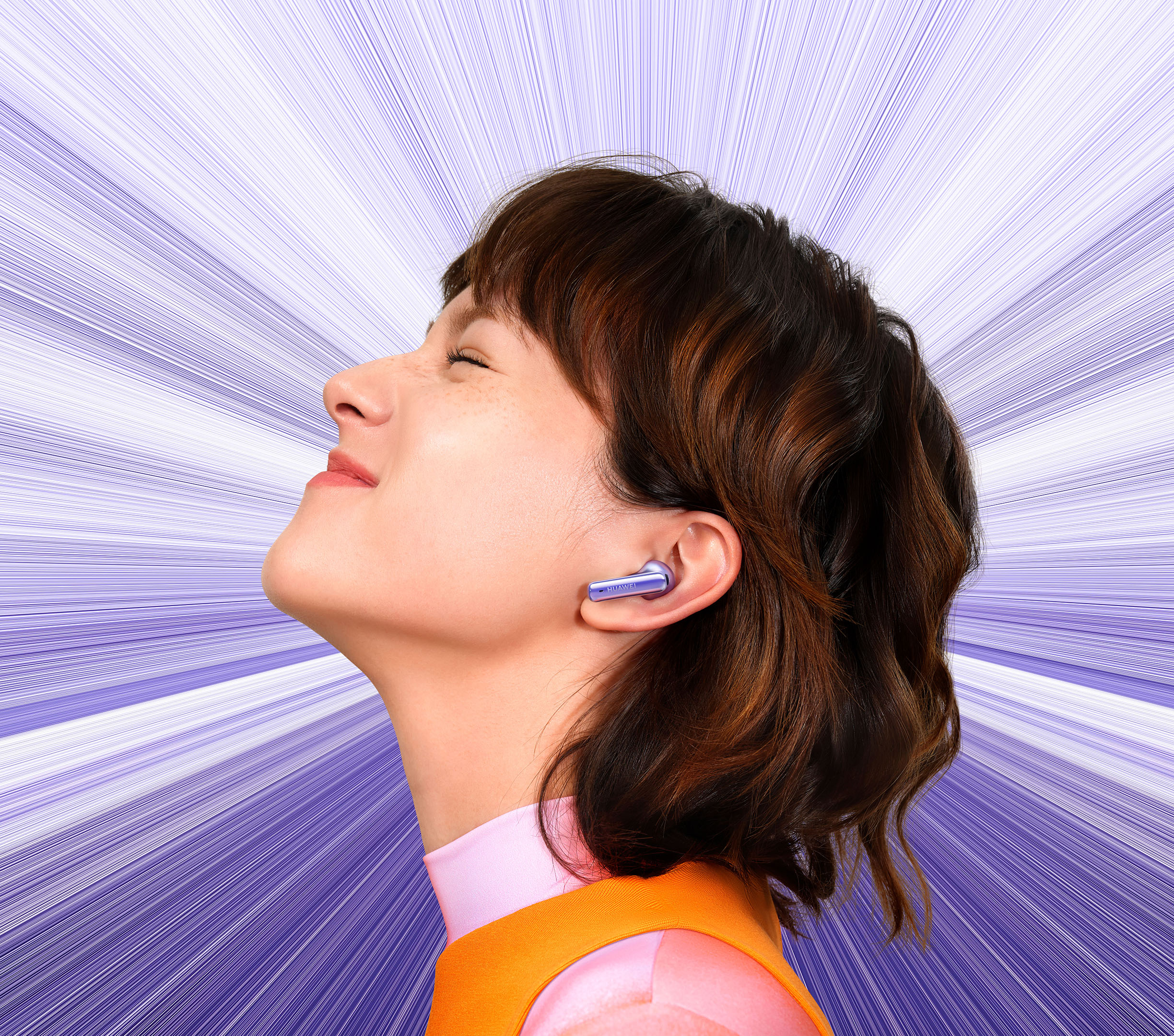 Kobieta z fioletowym tłem, w fioletowych słuchawkach i pomarańczowych ubraniach, patrzy w górę.