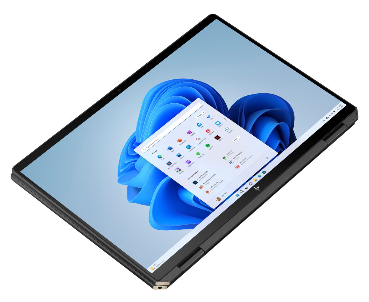 Laptop z ekranem wyświetlającym interfejs systemu Windows. Laptop jest otwarty na białej powierzchni.