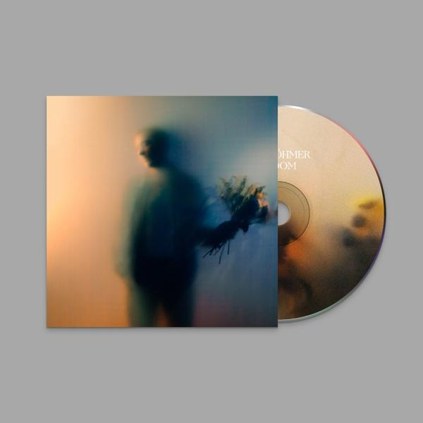 Eine CD in einer Hülle. Das Cover zeigt ein verschwommenes Bild einer Person, die Blumen hält. Der Hintergrund ist orange.
