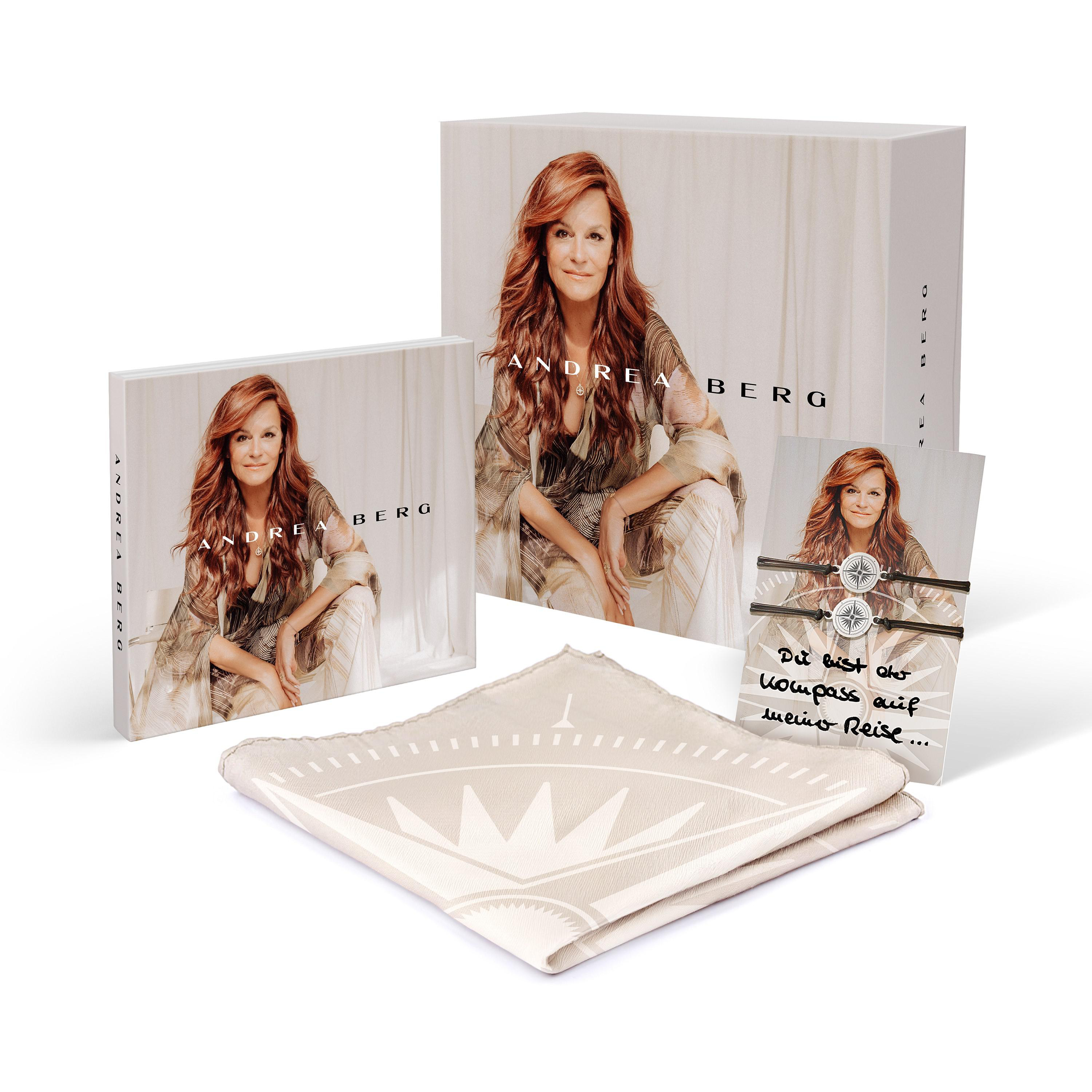 Mehrere Artikel von Andrea Berg-Merchandise: ein Buch, eine Box und ein Taschentuch mit Kompassdesign.