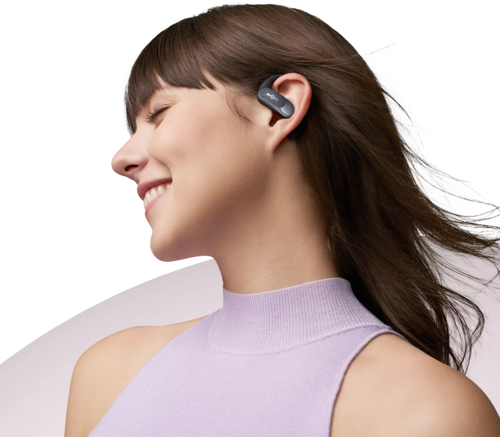 Una donna con un auricolare grigio, sorridente, con uno sfondo sfocato.