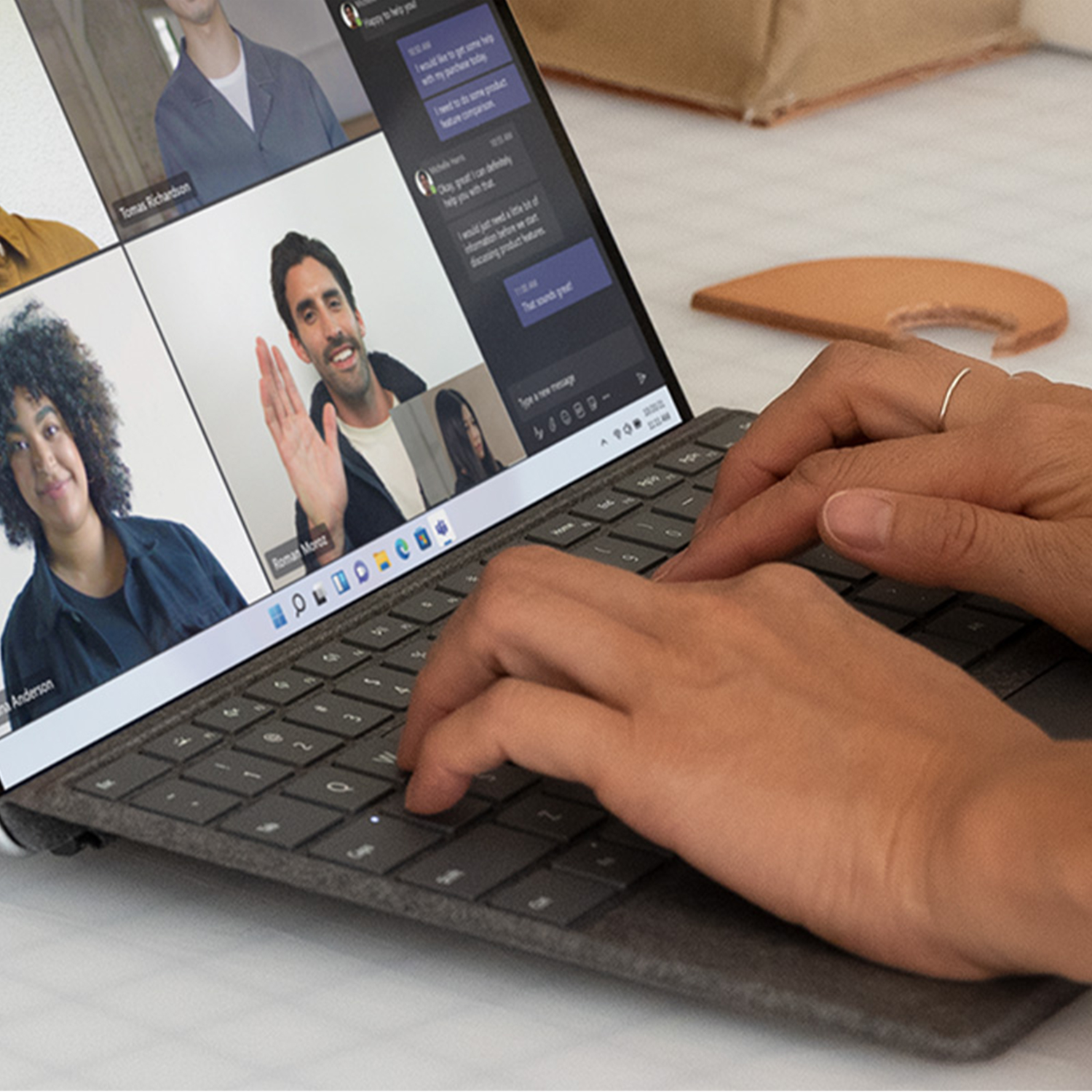 Person using laptop for video call. The screen displays multiple faces in a video chat.