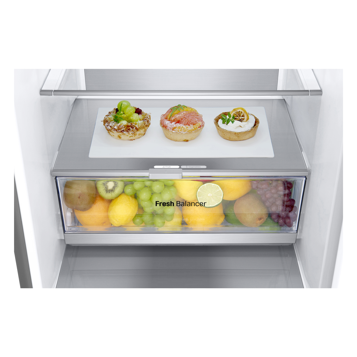 Intérieur d'un réfrigérateur avec fruits et pâtisseries sur étagères en verre, fond blanc.