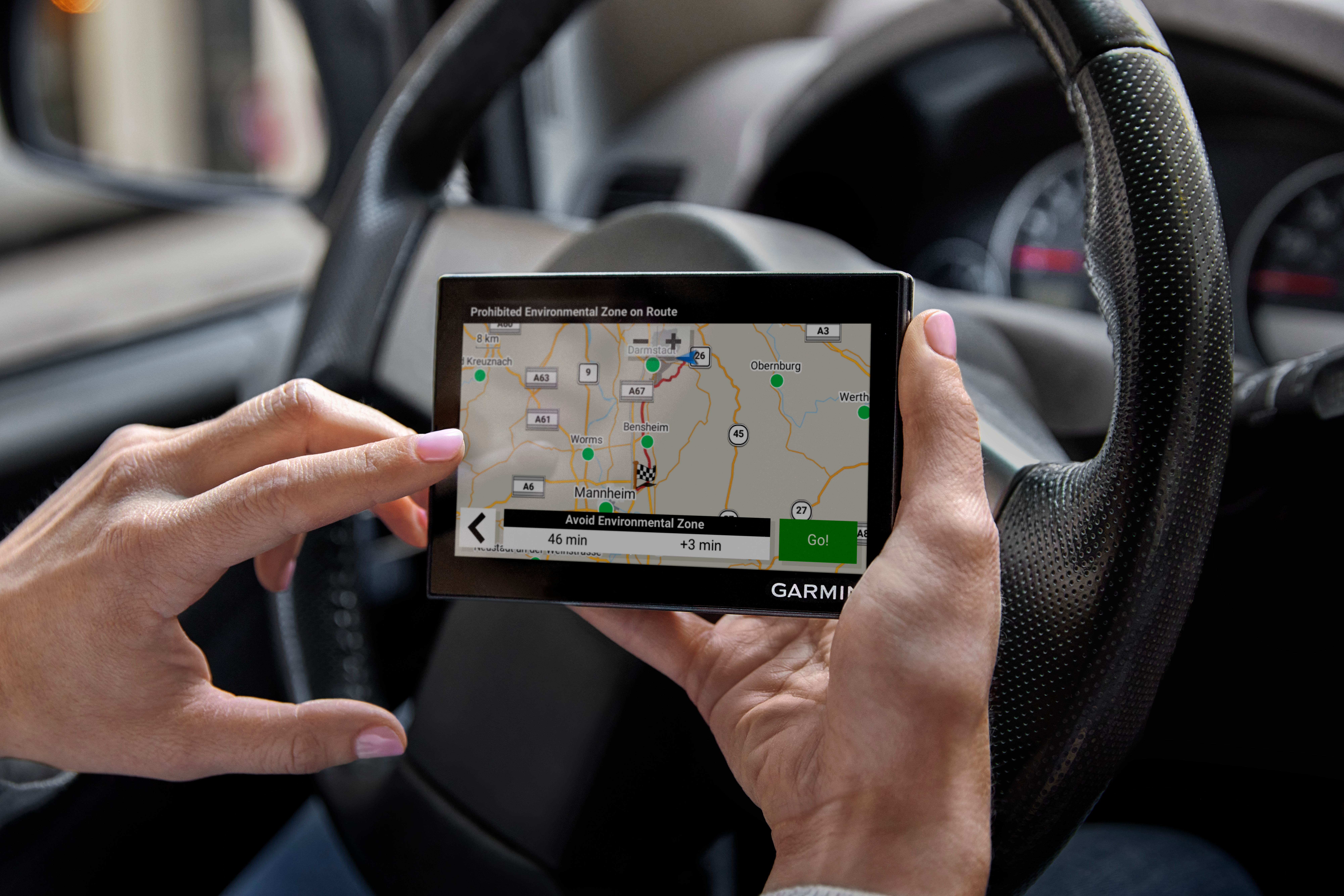 Una persona usa un GPS Garmin in auto. Lo schermo mostra una mappa con un percorso e una zona ambientale.