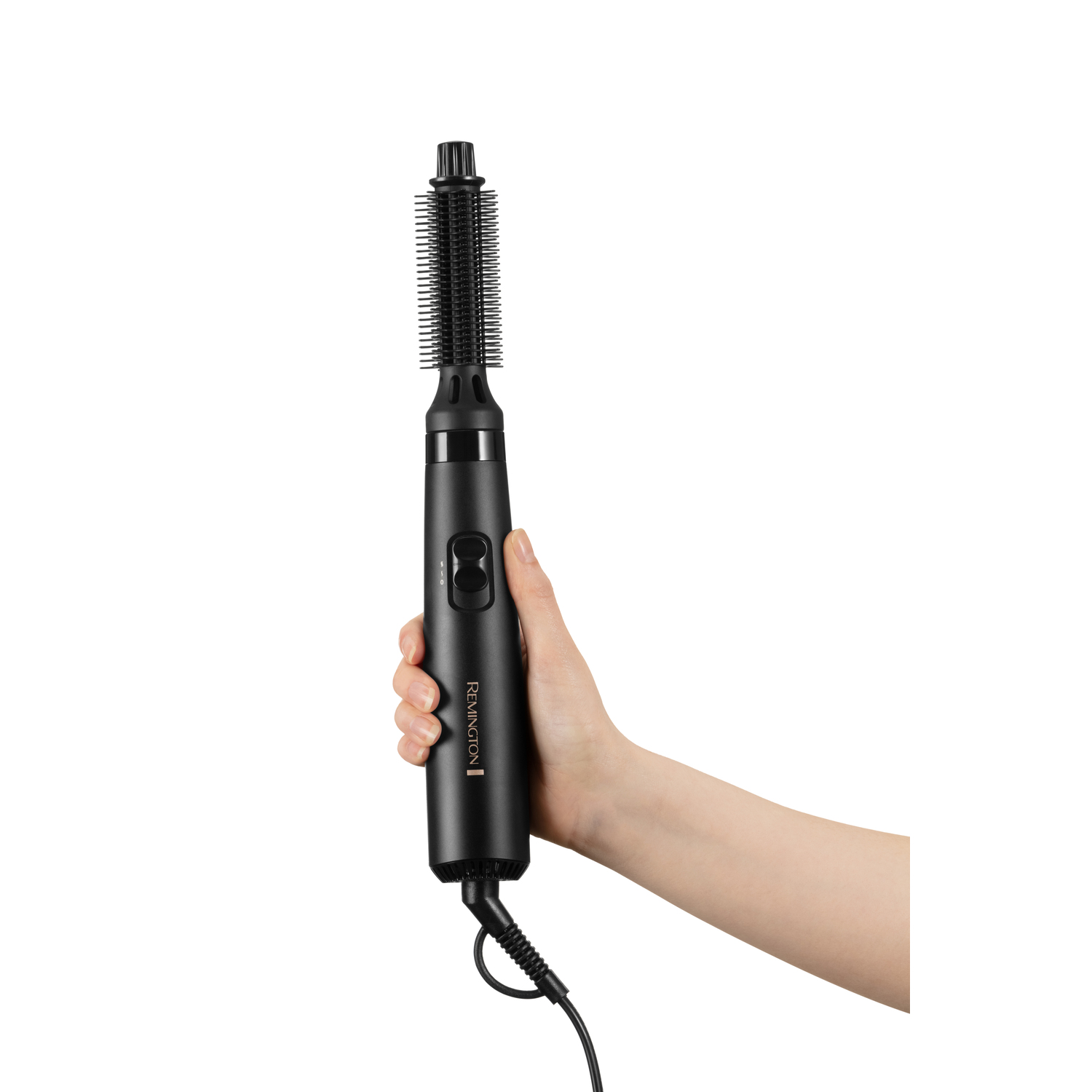 Main de femme tenant un styler Remington noir. Manche et brosse visibles.
