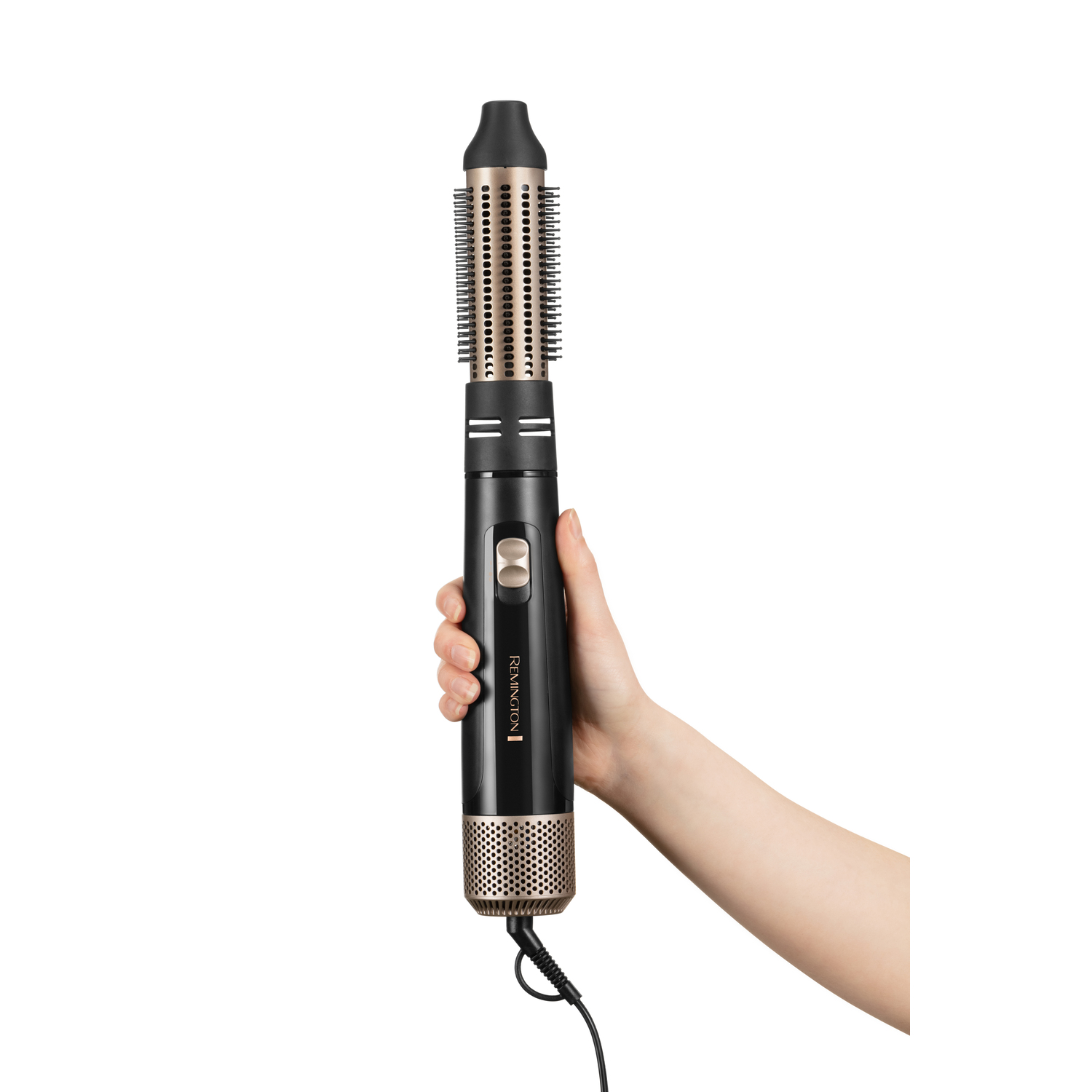 La main d'une femme tenant un styler capillaire Remington noir et doré, isolé sur fond blanc.