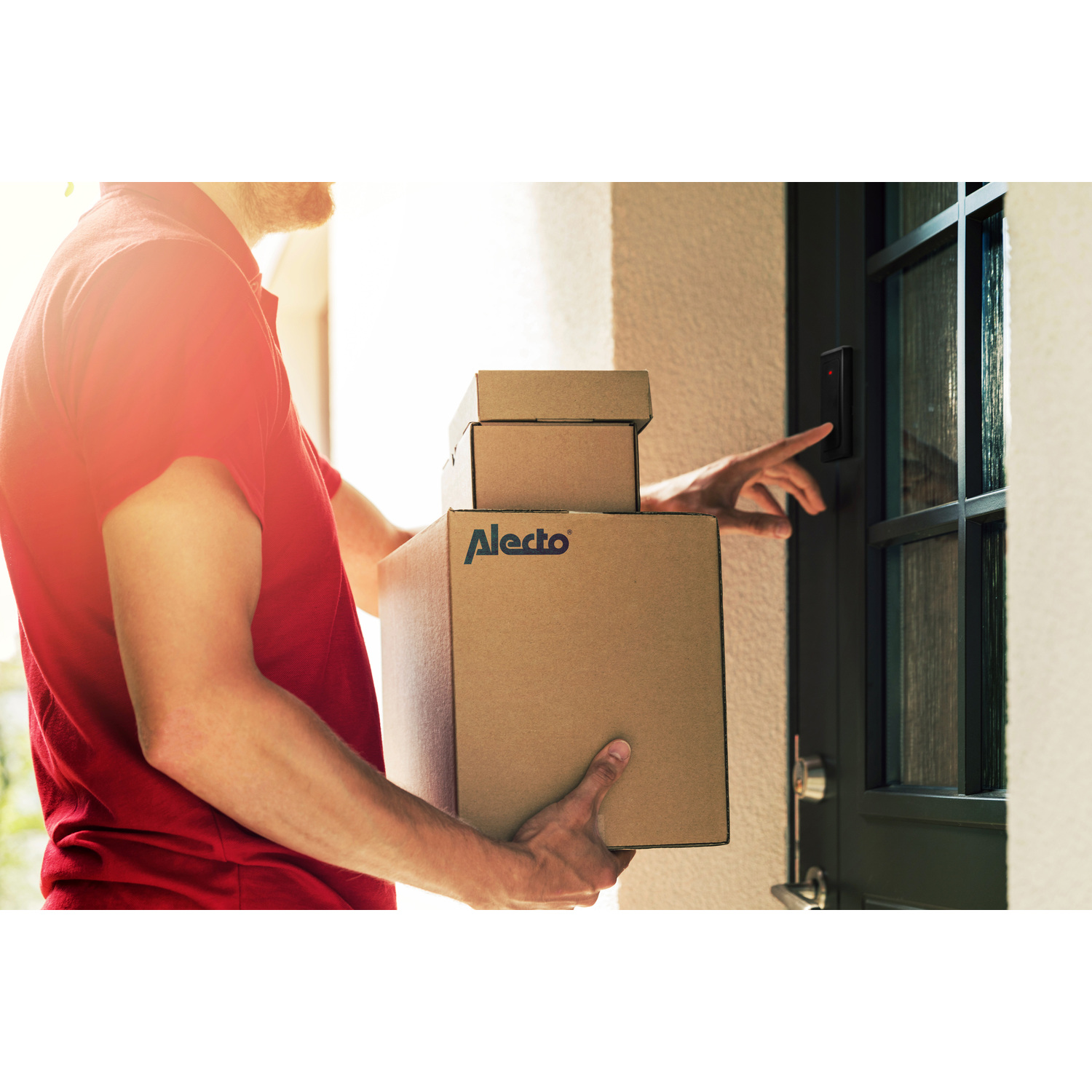 Delivery person holding boxes, reaching for a smart door lock. Sunlight.