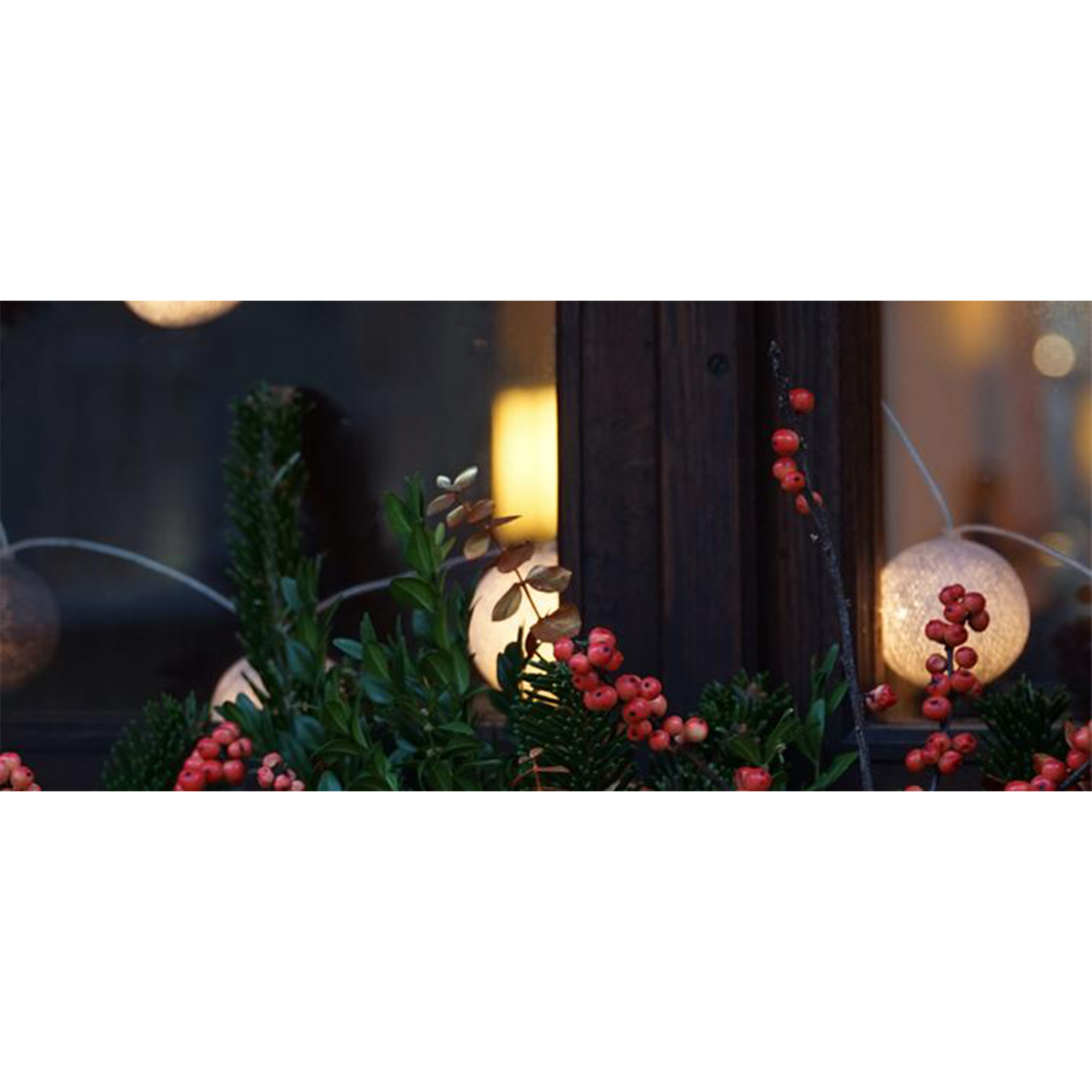 Decorazioni natalizie, luci e bacche su una finestra. Legno scuro e luci.