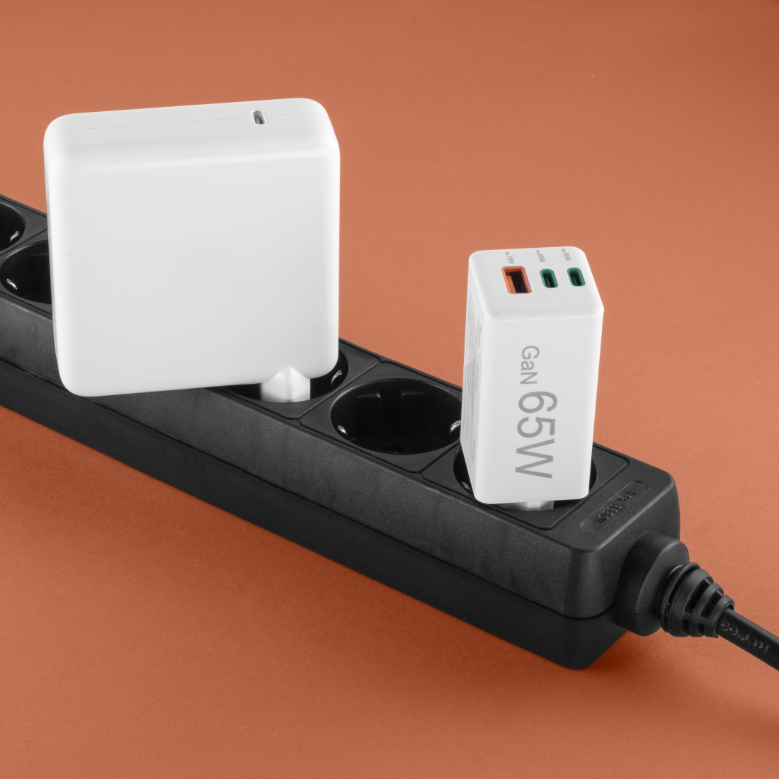 Un adaptador de corriente blanco y una regleta negra enchufados entre sí.