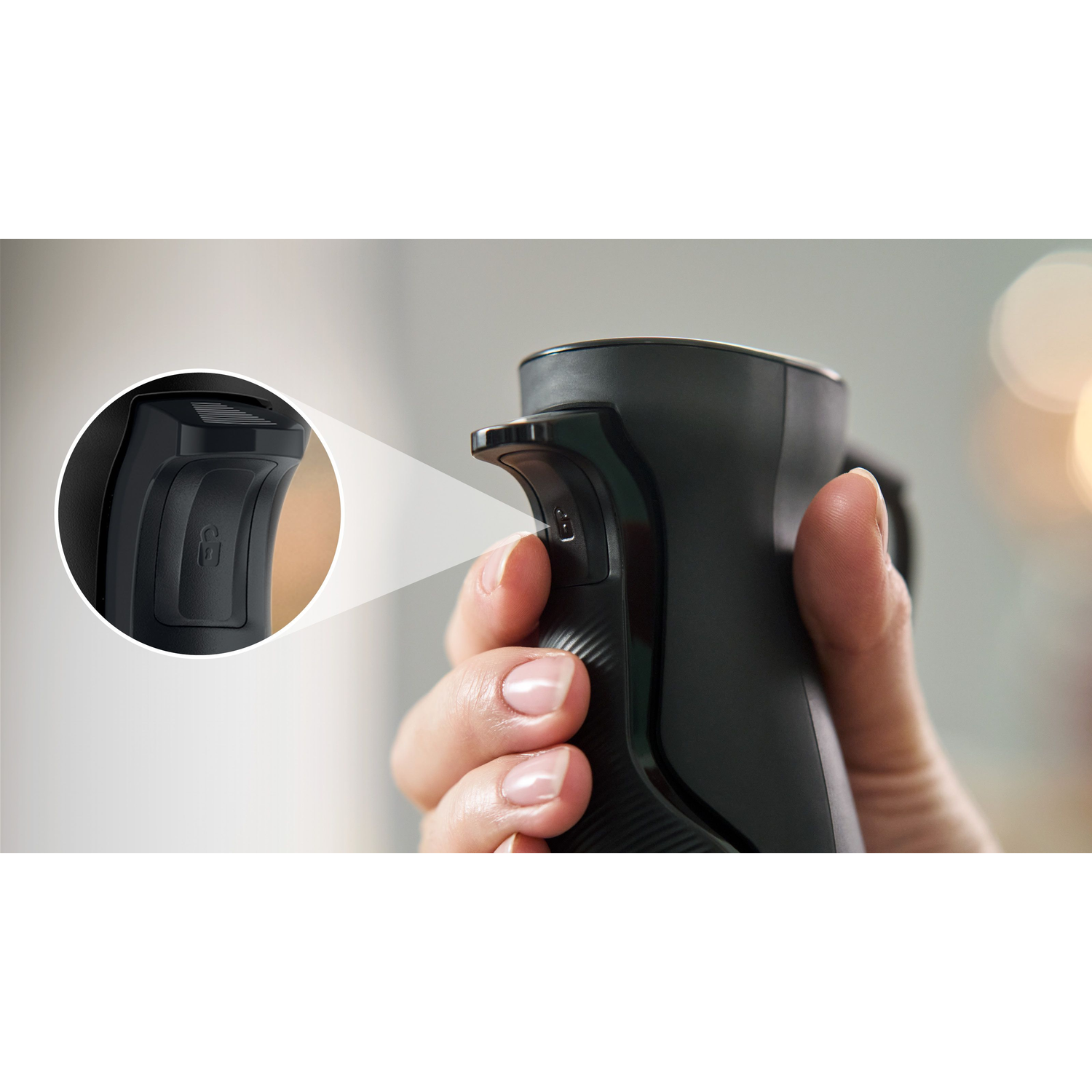 Hand holding a black device, pressing a button. A close-up shot with a white background.