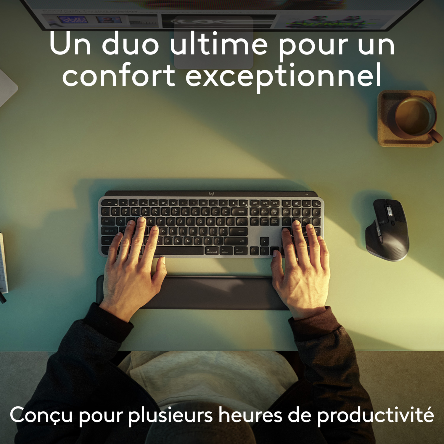 Mains sur clavier et souris sur bureau vert, tasse à café en haut à droite.