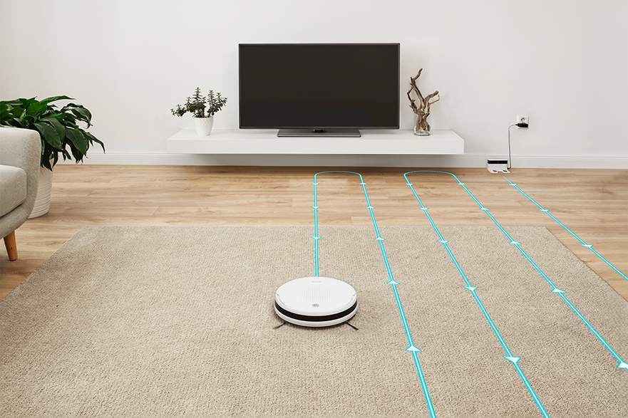 Robot porszívó egy szőnyegen, kék vonalakkal, amelyek a tisztítási útvonalat mutatják.