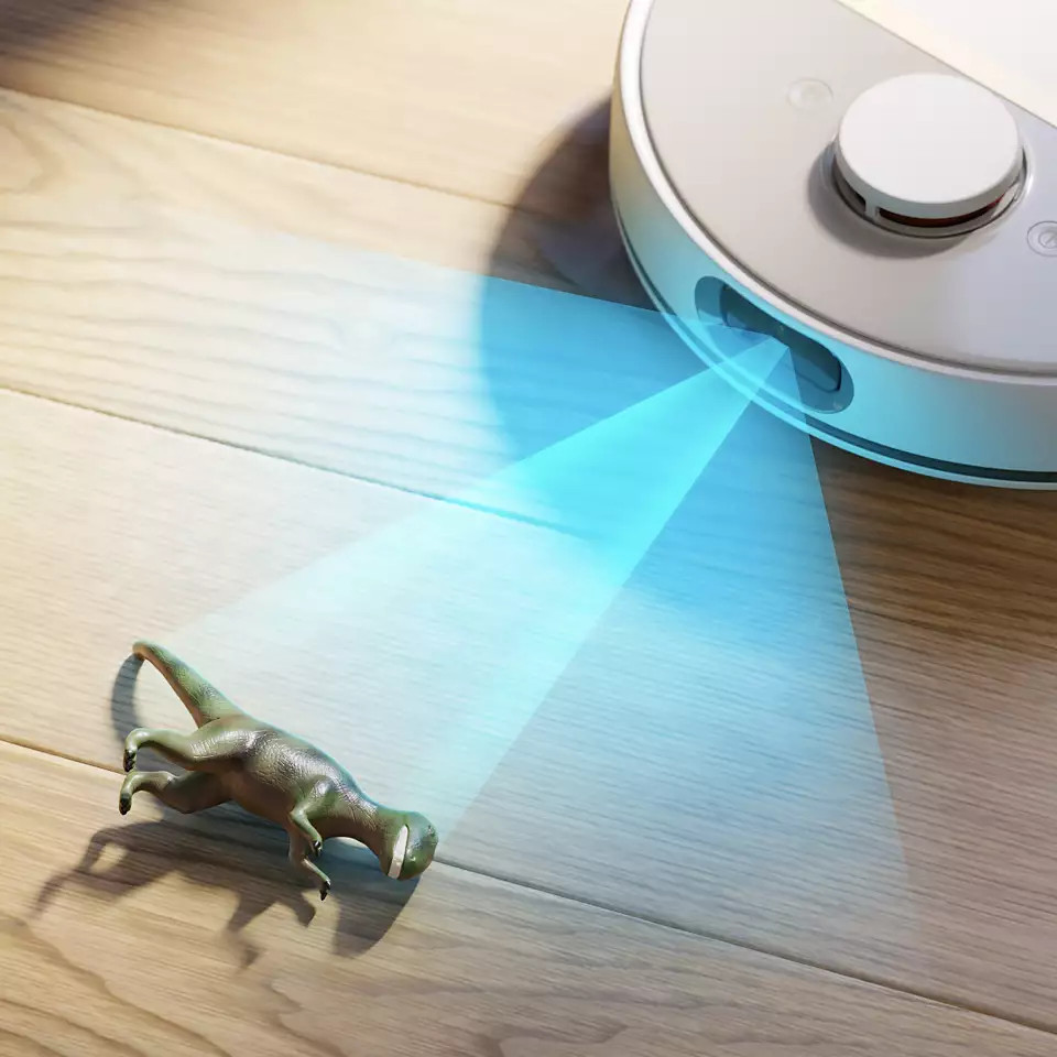 Robot odkurzający z zabawką dinozaura na podłodze, a także wyświetlana niebieska wiązka światła.
