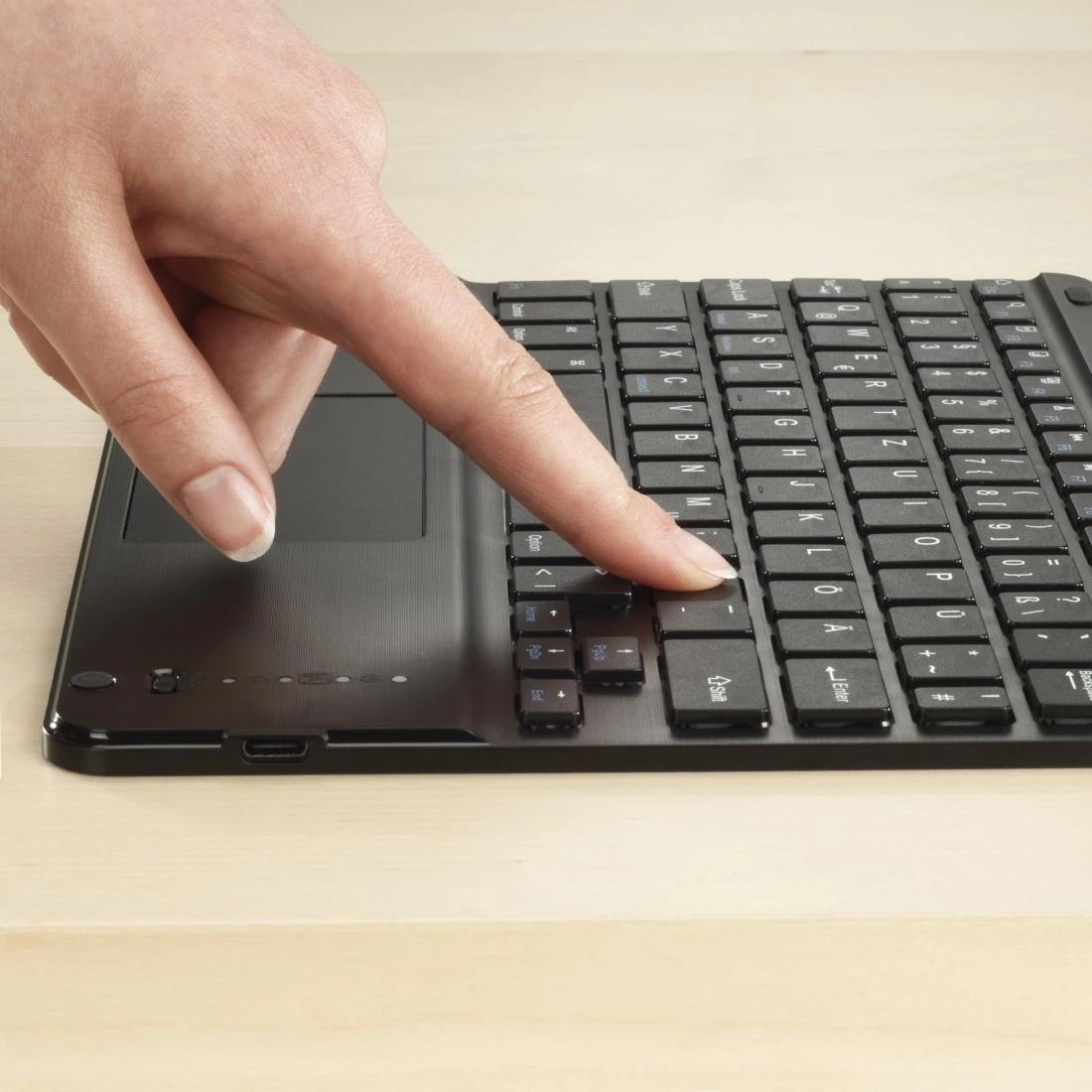 Une main appuie sur la touche 'Entrée' d'un clavier noir.