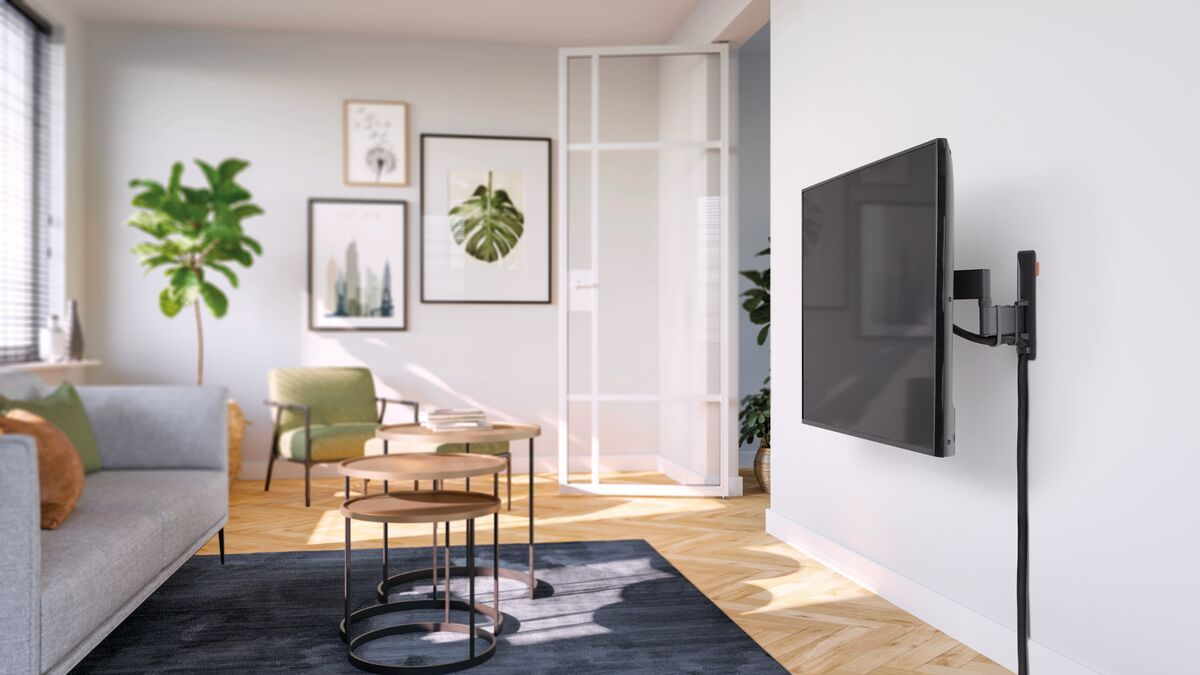 Wohnzimmer mit einem an der Wand montierten Fernseher. Möbel umfassen ein Sofa und Couchtische.