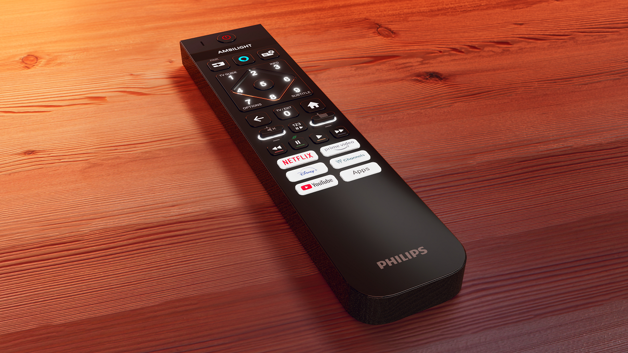 Télécommande TV noire sur table en bois, avec boutons et logos, lumière chaude.