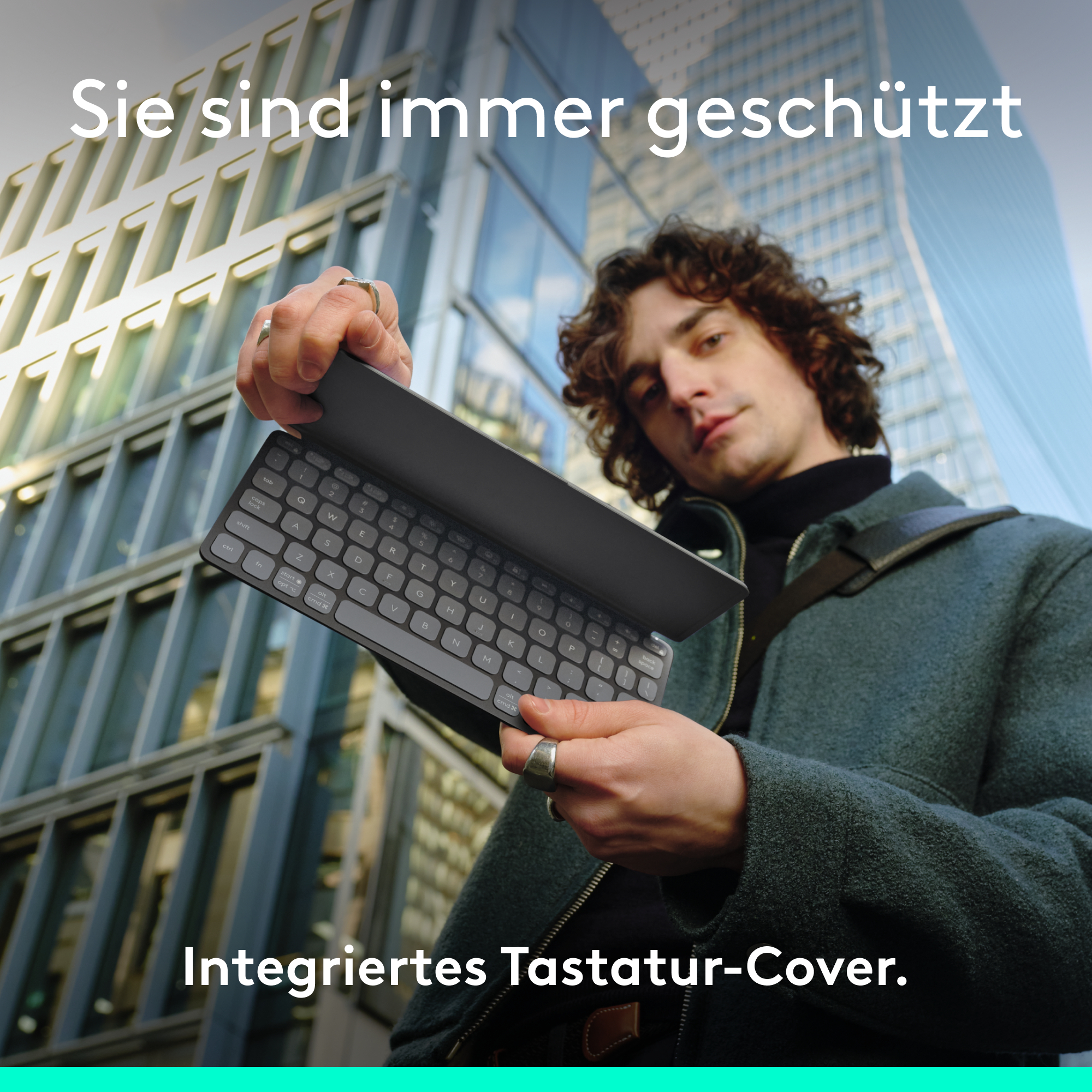Ein Mann hält eine Tastaturabdeckung vor einem Glasgebäude.