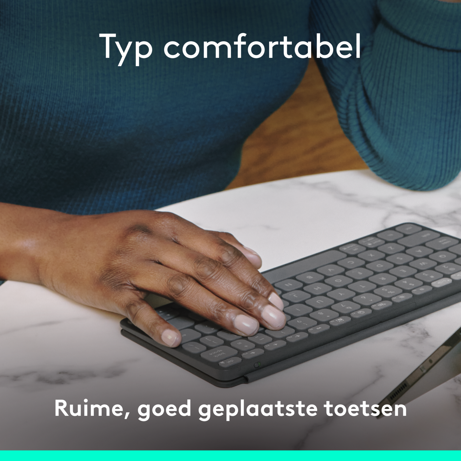 Hand die typt op een zwart toetsenbord op een wit marmeren oppervlak.