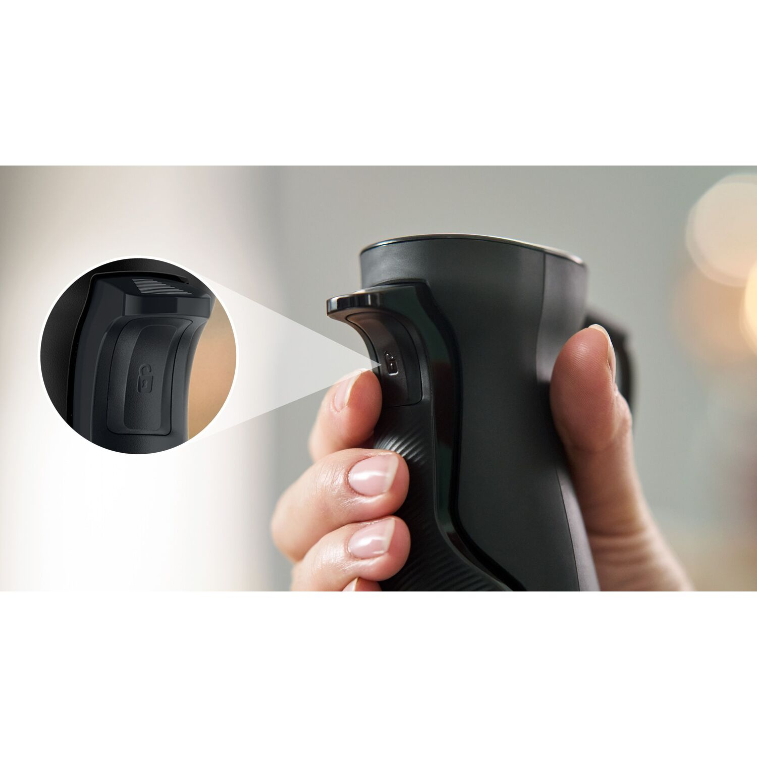 A hand holding a black blender with a lock button.