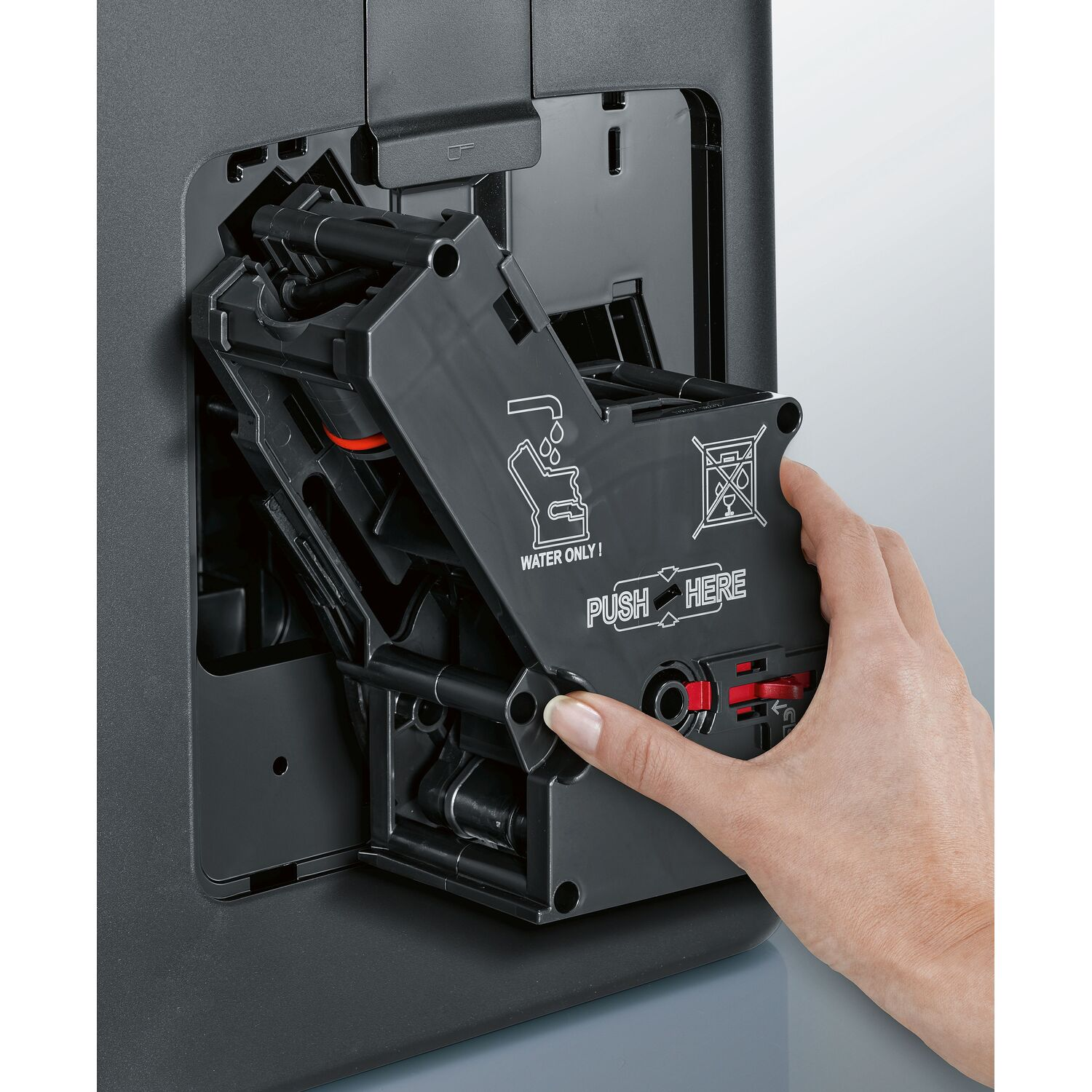 A person's hand interacting with a coffee machine component.