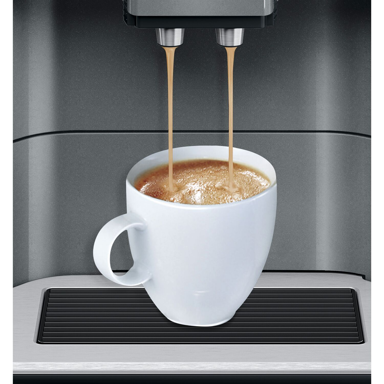 Coffee pouring from a machine into a white mug. Close-up.