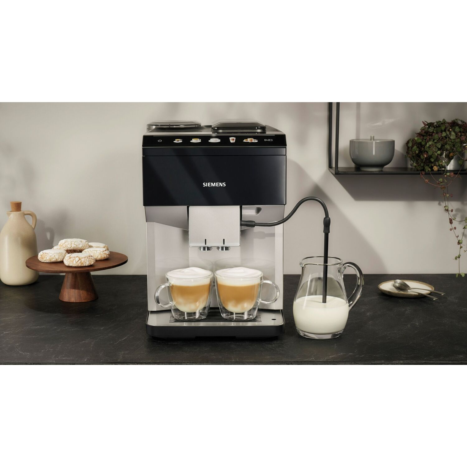 Machine à café Siemens avec deux tasses de latte. Pichet de lait et biscuits sur les côtés.