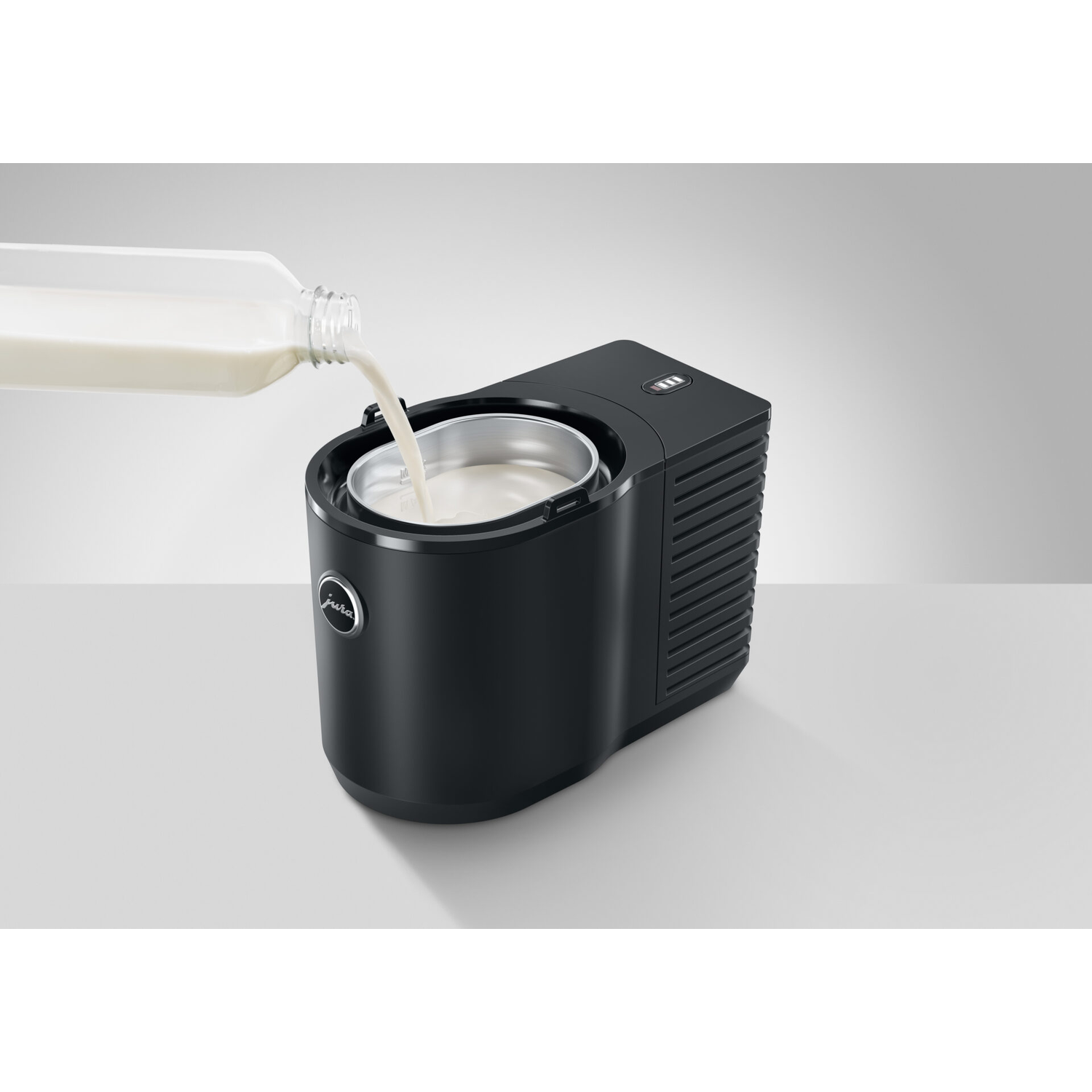 Black ice cream maker with milk being poured inside.