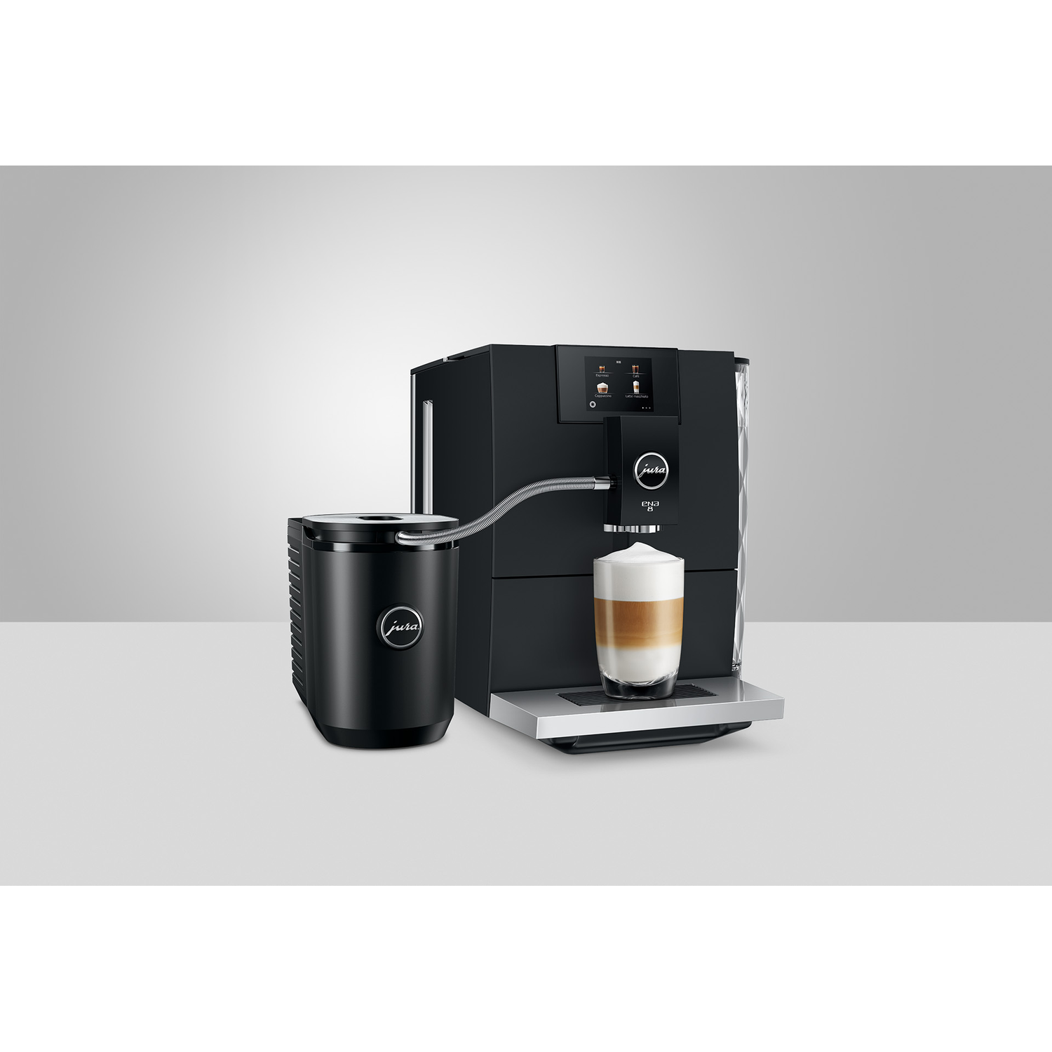 A black Jura coffee machine with milk frother, dispensing a layered latte into a glass on a white surface.