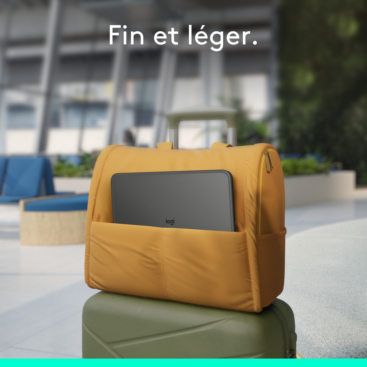 Sac à dos jaune sur une valise verte. Une tablette est dans le sac. Arrière-plan flou d'un bâtiment.