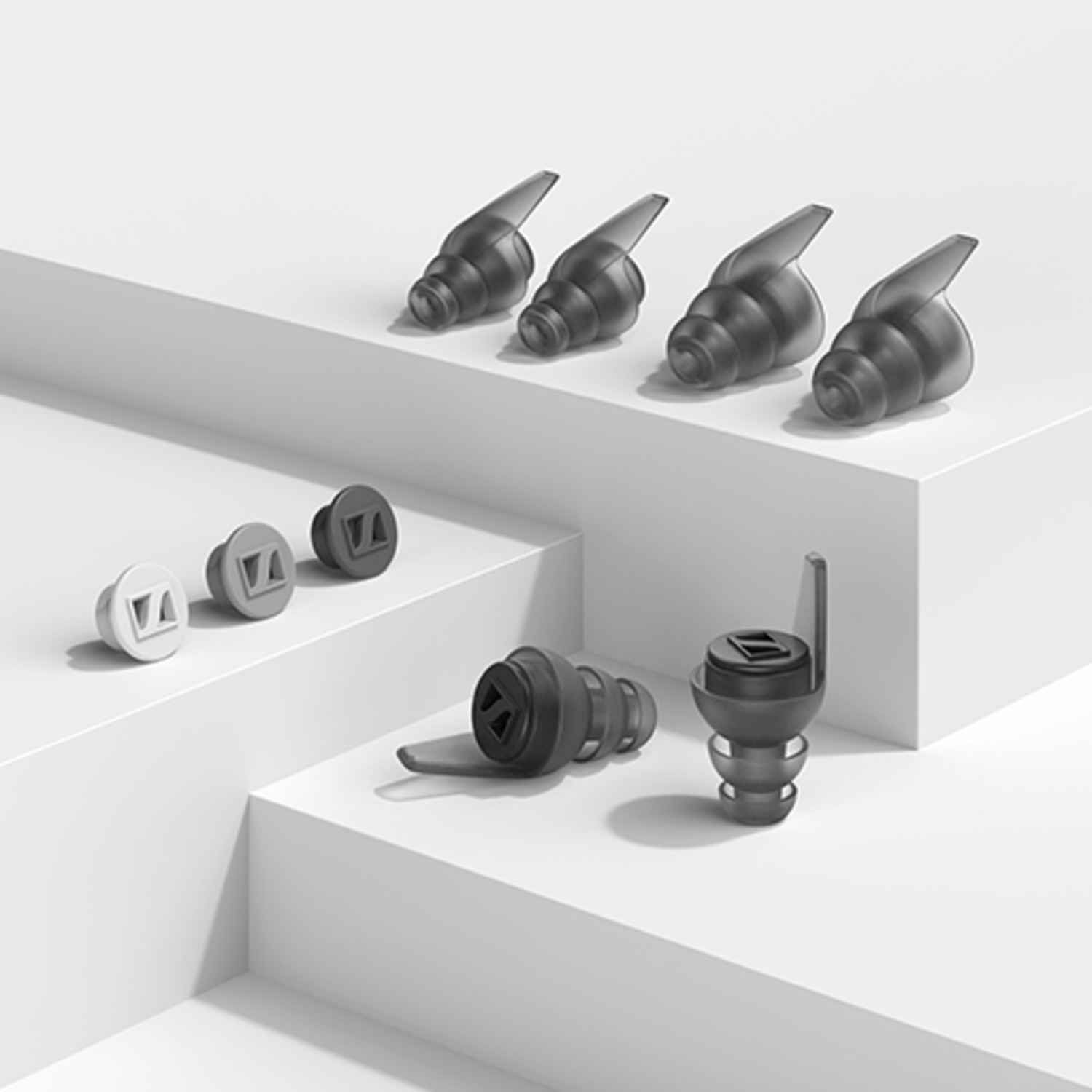 Plusieurs bouchons d'oreille en formation étagée, de formes et tailles différentes, sur une surface blanche.