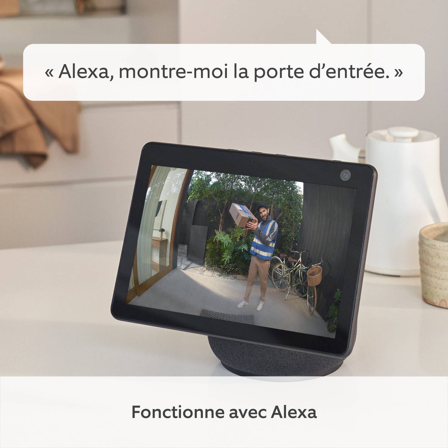 Affichage intelligent noir montrant un homme avec un colis. Bulle de texte dit: "Alexa, montre-moi la porte."