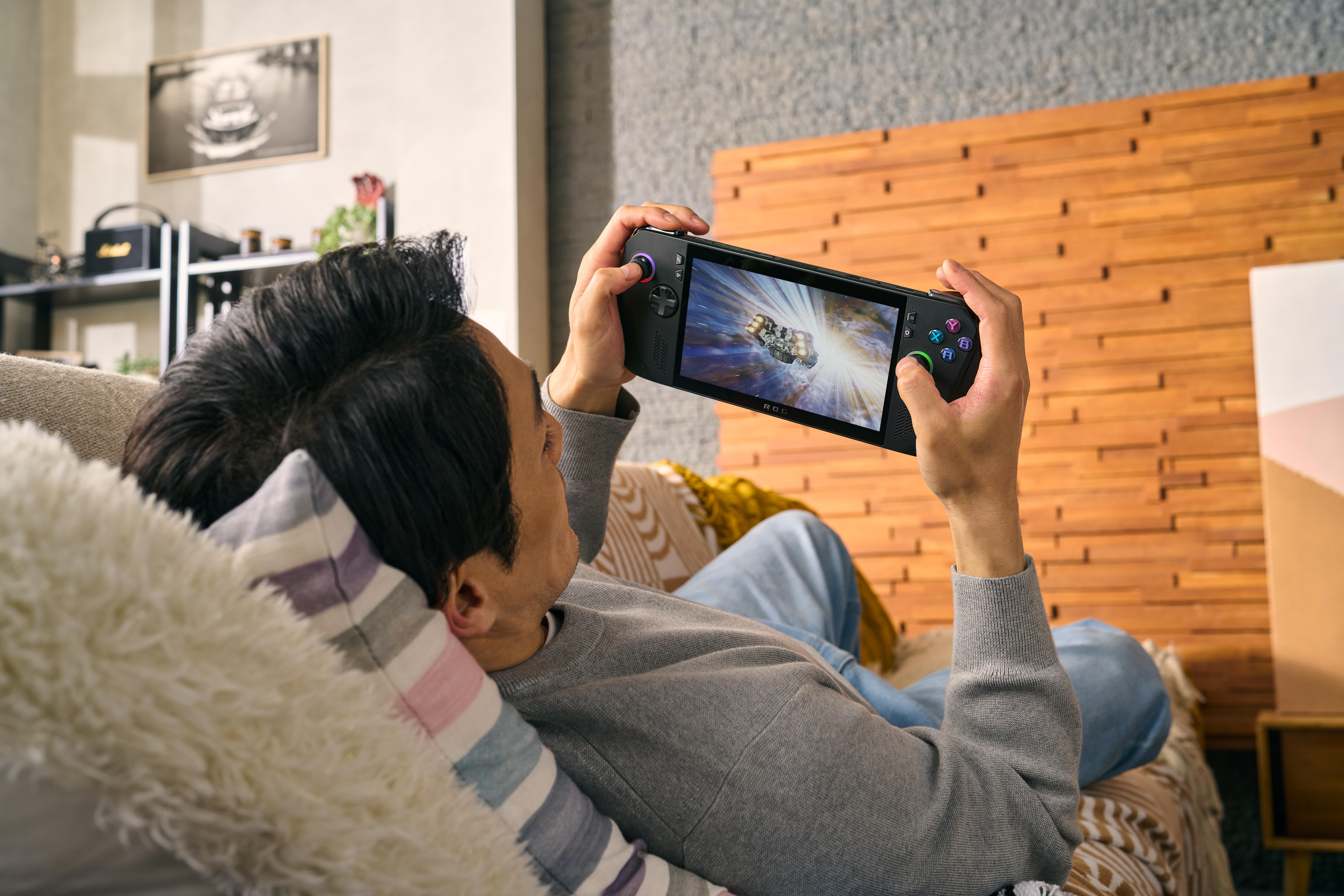 Eine Person, die sich auf einer Couch zurücklehnt und eine tragbare Videospielkonsole spielt.
