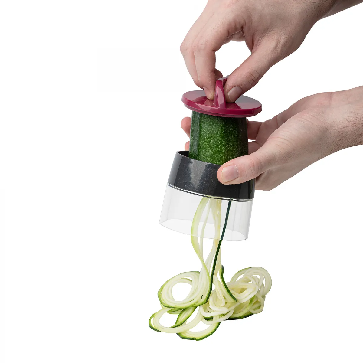 Manos usando un espiralizador para cortar un calabacín en espirales.