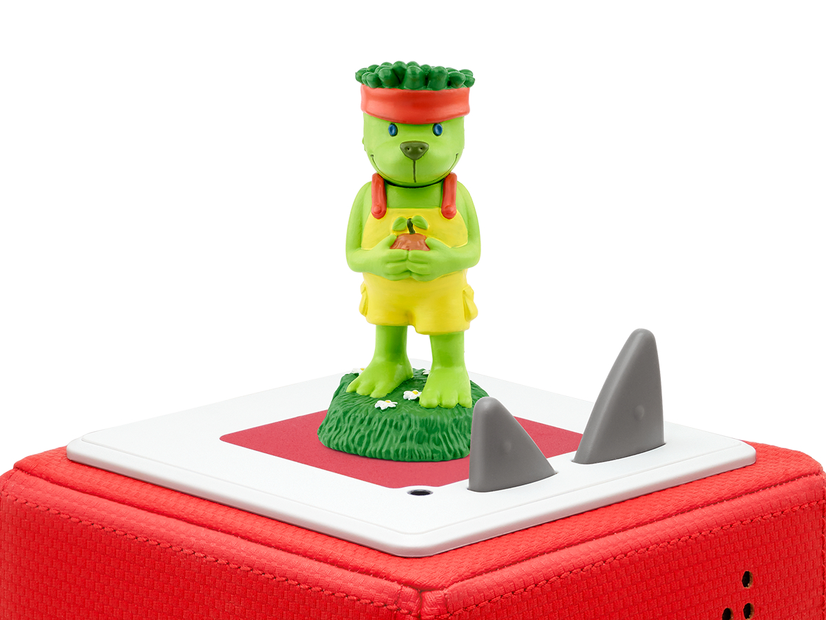 Spielzeugfigur eines Bären mit grünem Kopf und gelber Kleidung, auf roter Plattform.