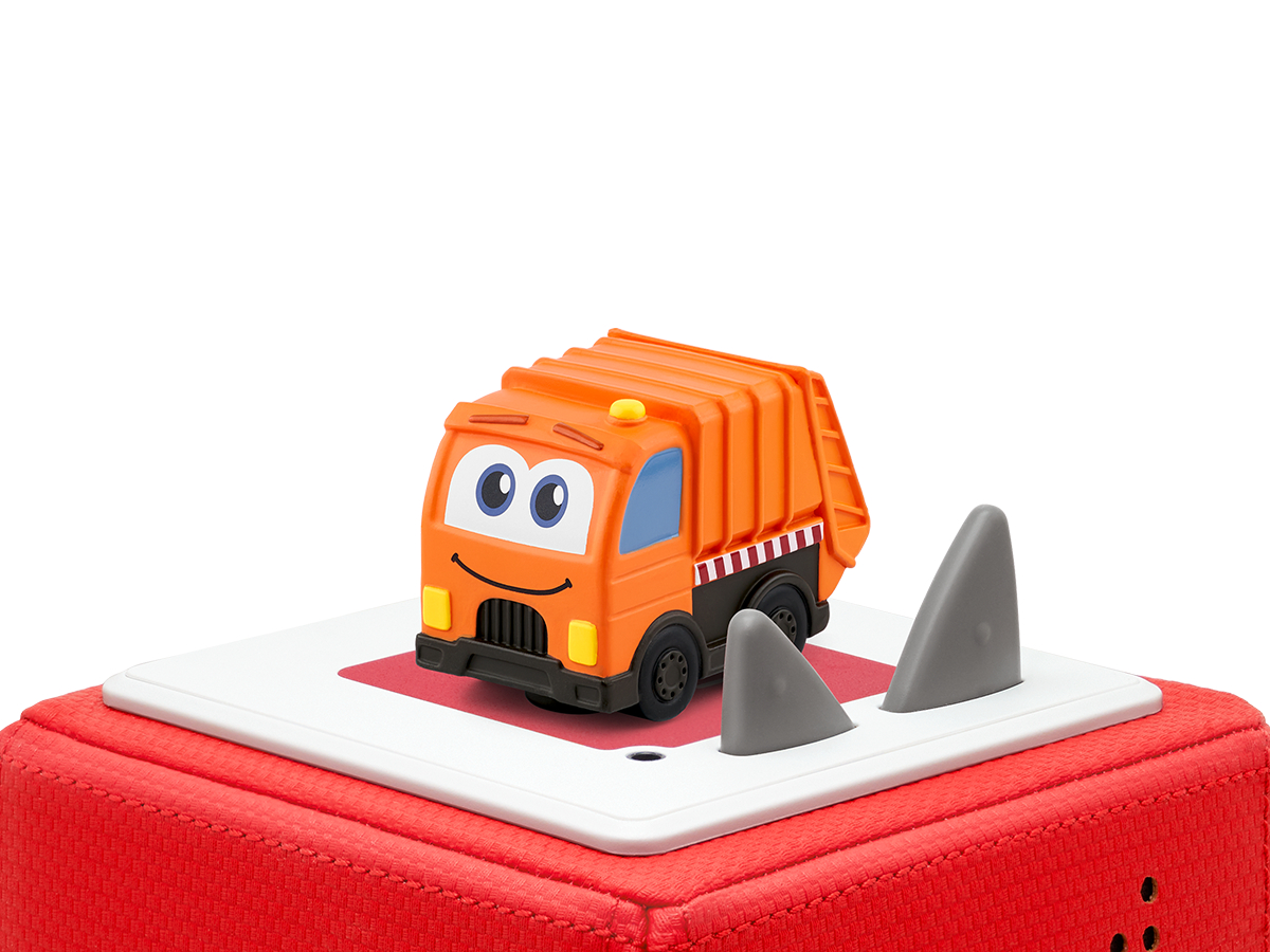 Oranger Spielzeug-Müllwagen mit Haifischflossen auf roter Oberfläche. Weißer Hintergrund.