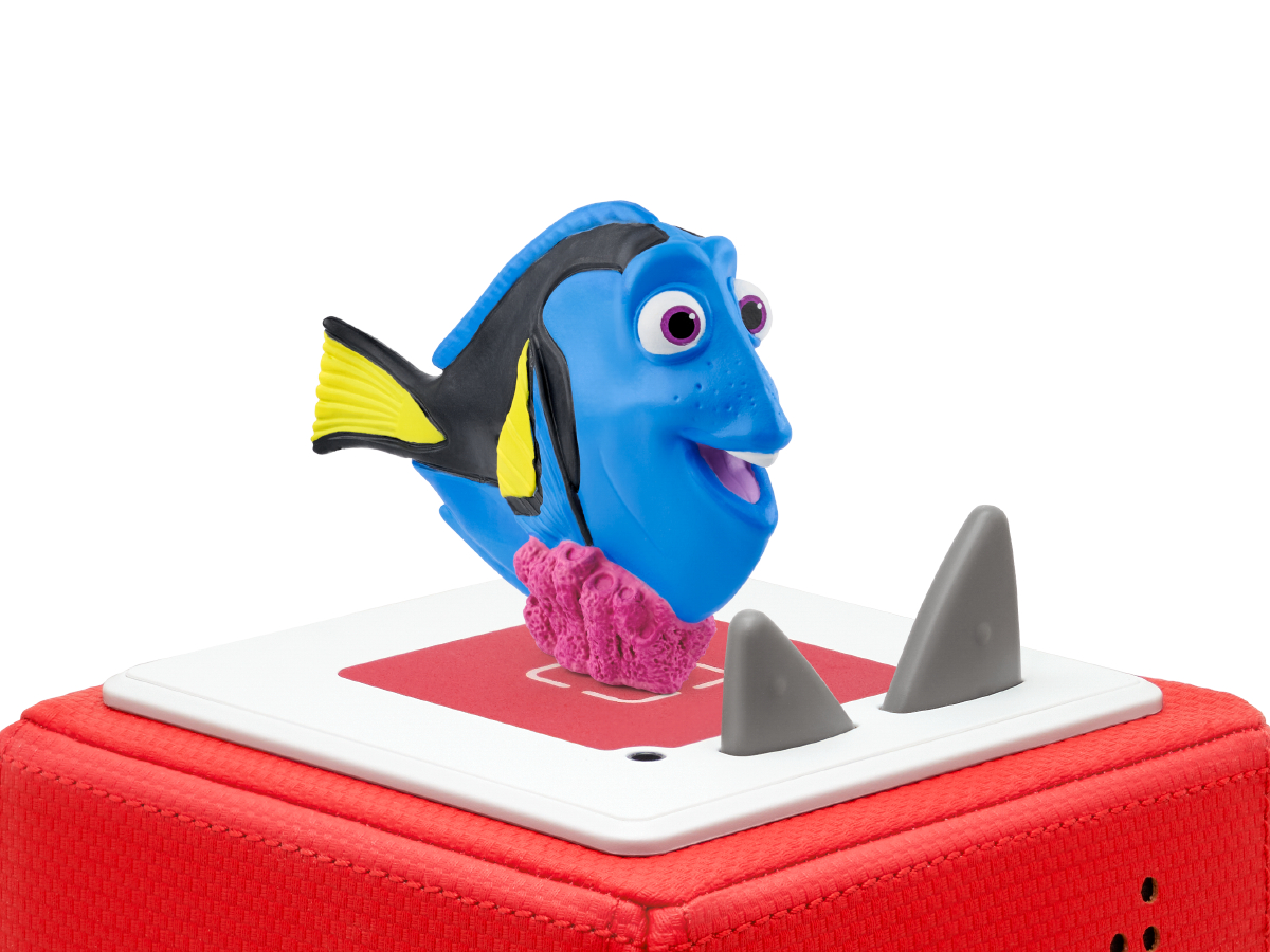 Dory-Spielzeug auf einer roten Box. Zwei graue Haifischflossen sind rechts.