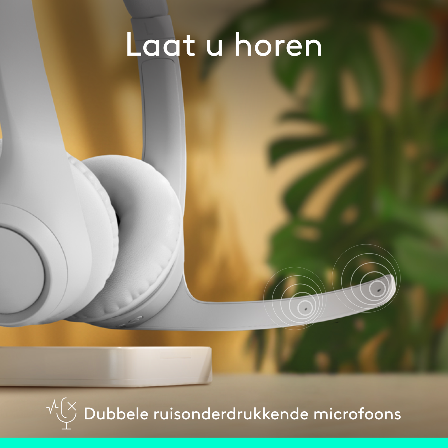 White headset with microphone on a stand, with a blurred green plant in the background.