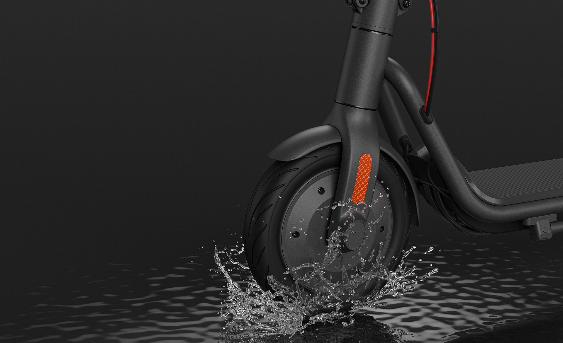 Koło hulajnogi elektrycznej, z którego tryska woda. Znajduje się na ciemnej, odblaskowej powierzchni.