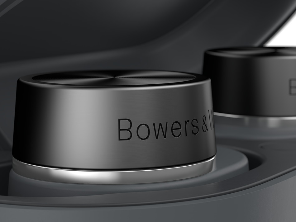 Zbliżenie dwóch czarnych słuchawek z logo Bowers & Wilkins, w ciemnym etui ładującym.