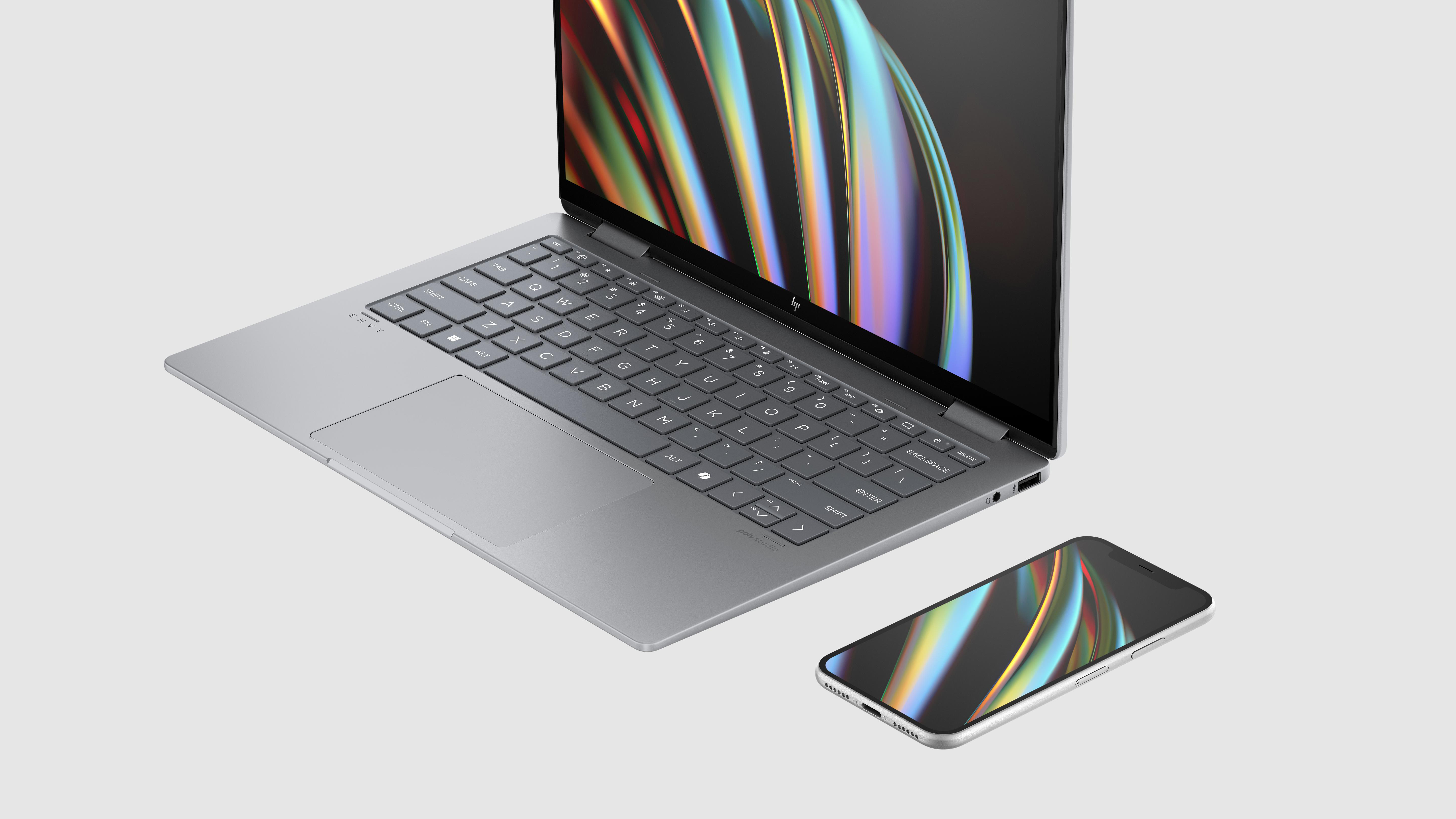 Laptop und Telefon auf Weiß. Laptop ist offen, Telefon liegt daneben.