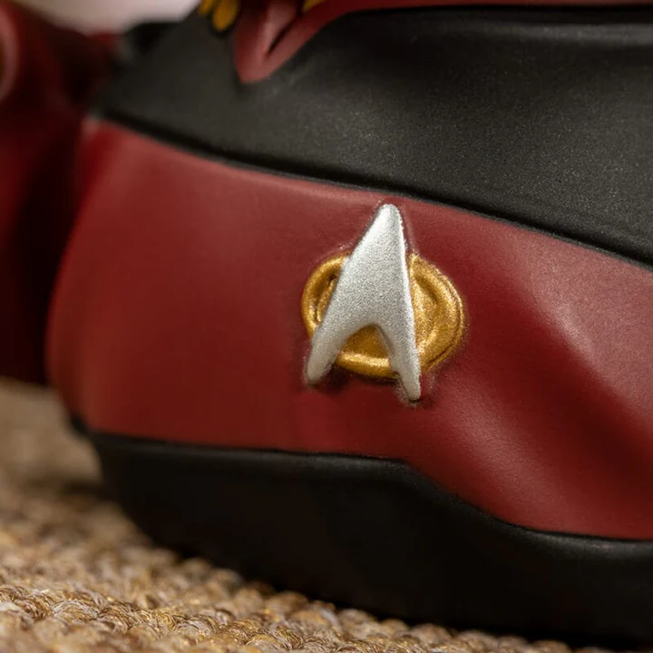 Közelkép egy Star Trek jelvényről egy Star Trek figura egyenruháján.