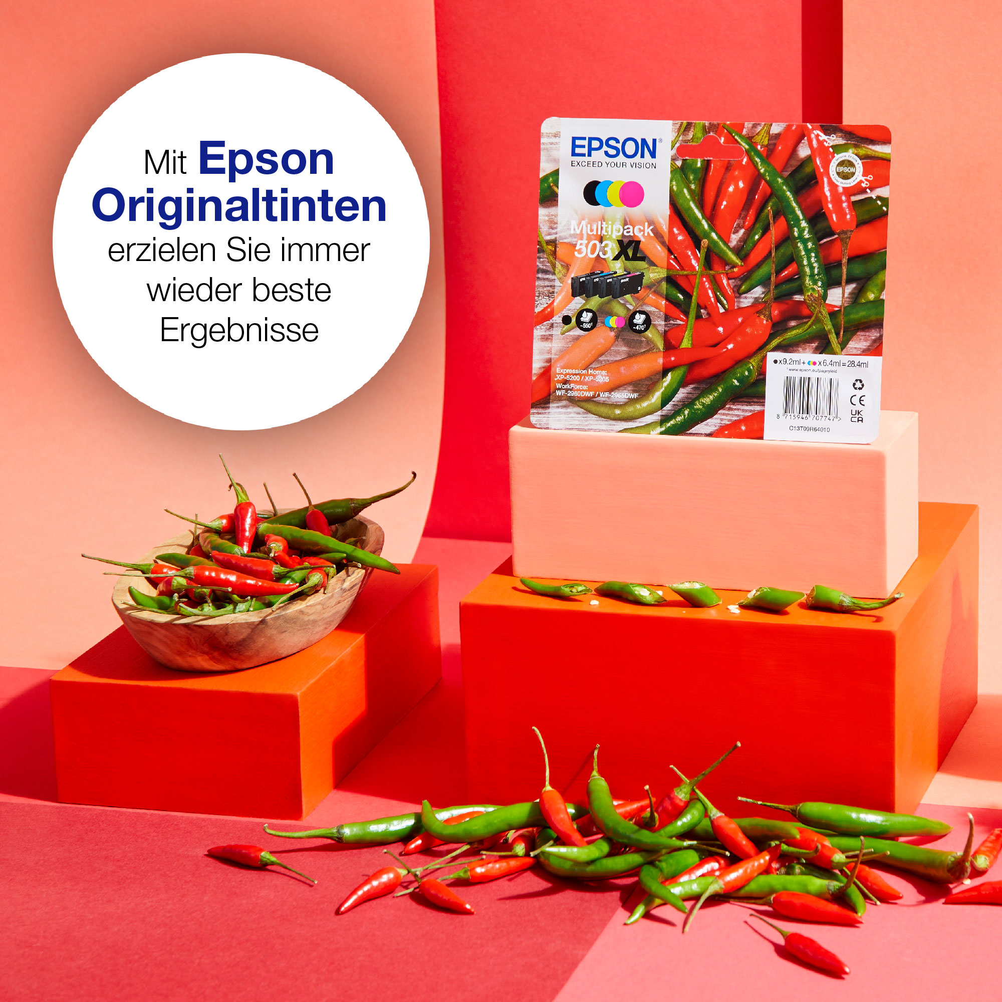 Rote Paprika in einer Holzschale und auf roter Oberfläche, mit Epson Tintenpackung.