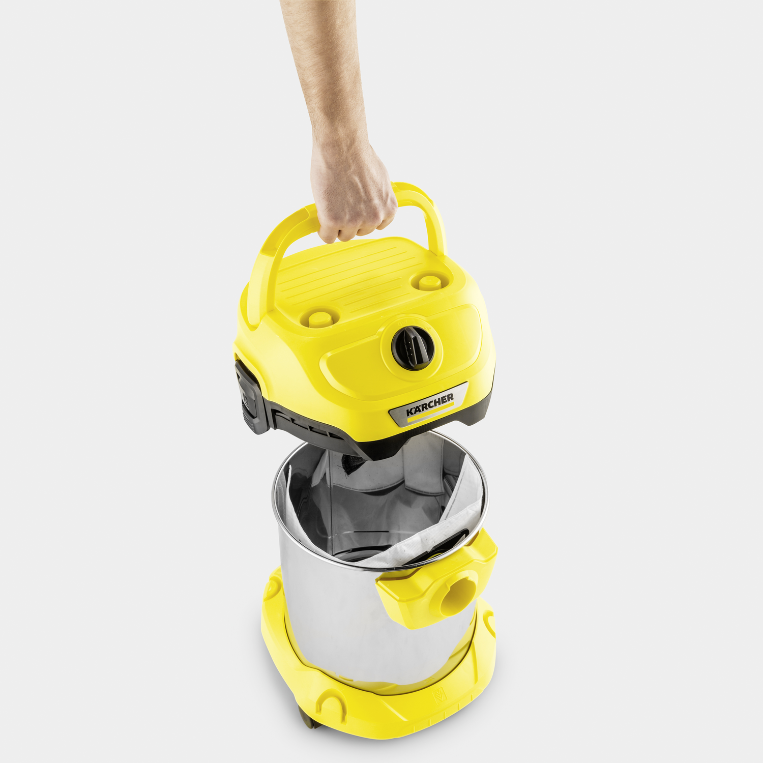 A hand lifting the yellow top off a yellow and silver vacuum cleaner.