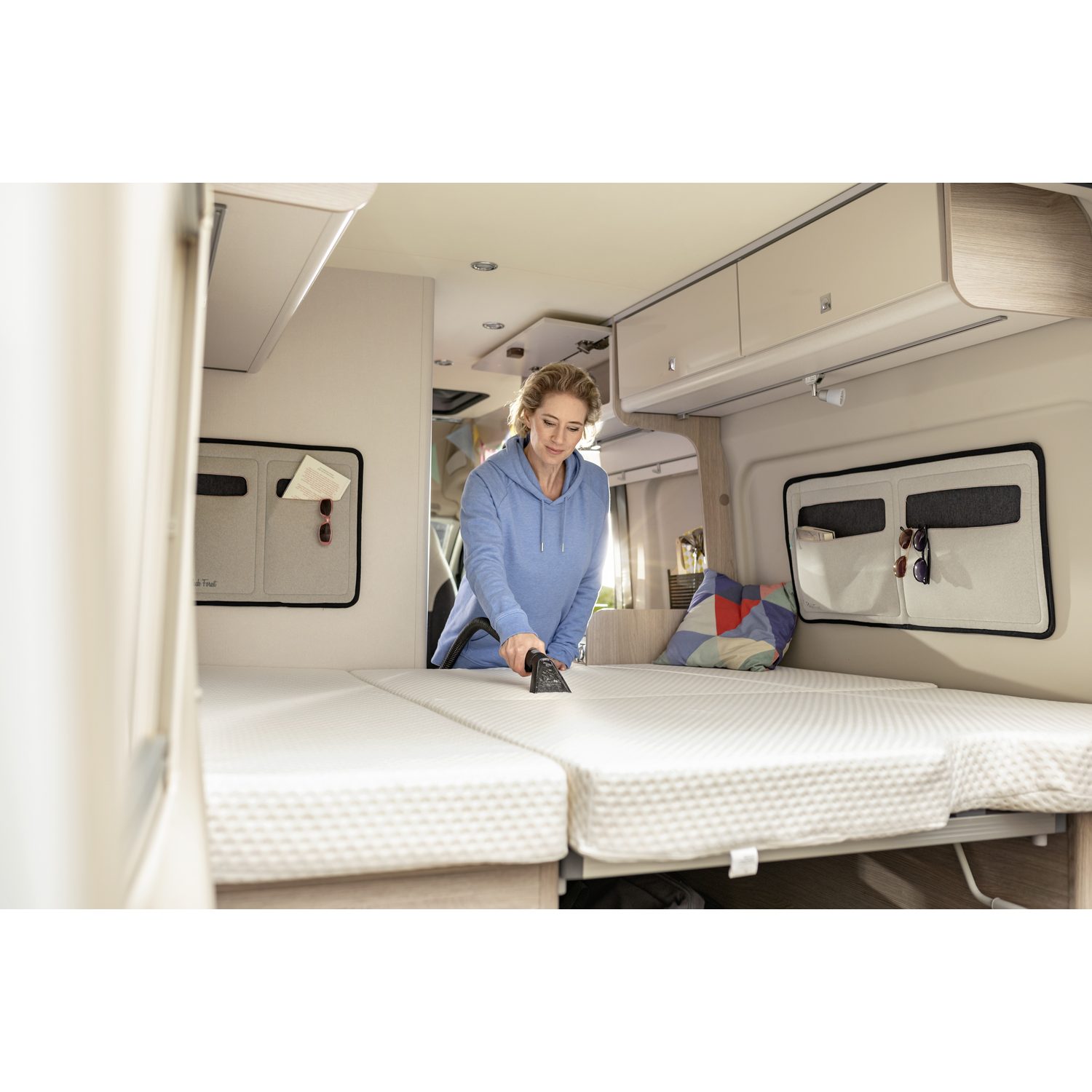 Femme passant l'aspirateur sur un matelas dans un camping-car.