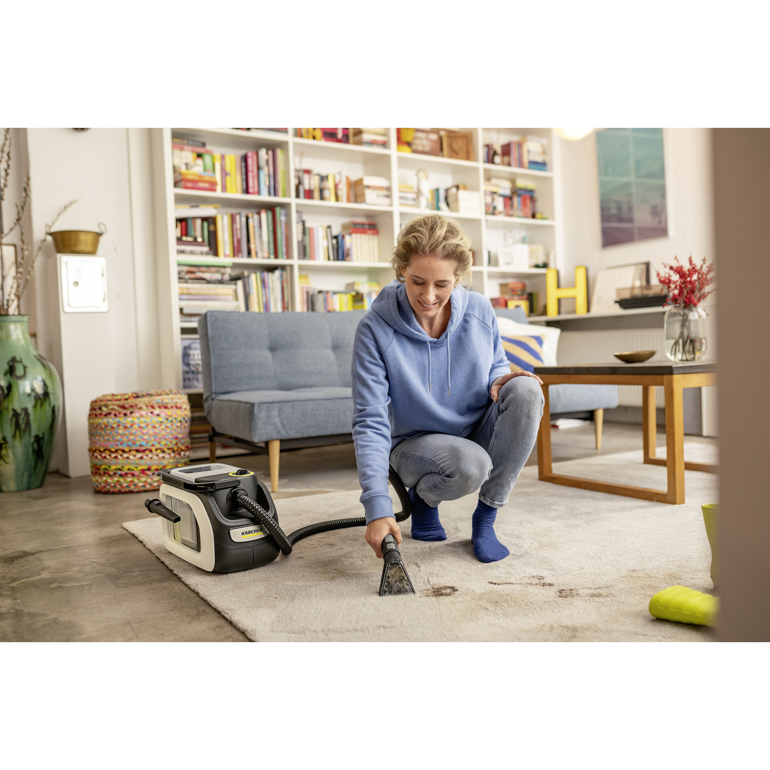 Femme nettoyant un tapis avec un nettoyeur de tapis.