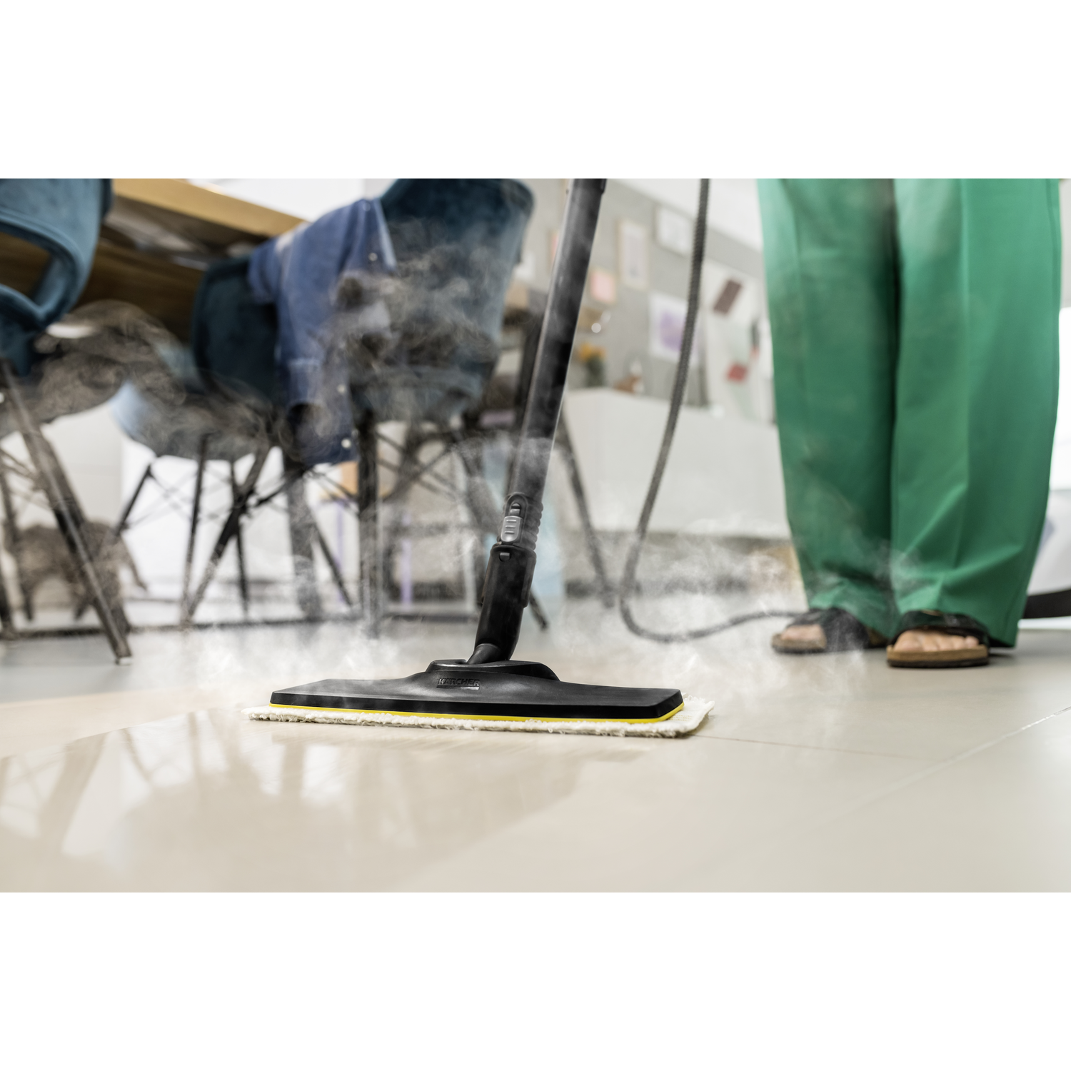 A person using a steam cleaner on a tiled floor. Steam is rising from the cleaner.