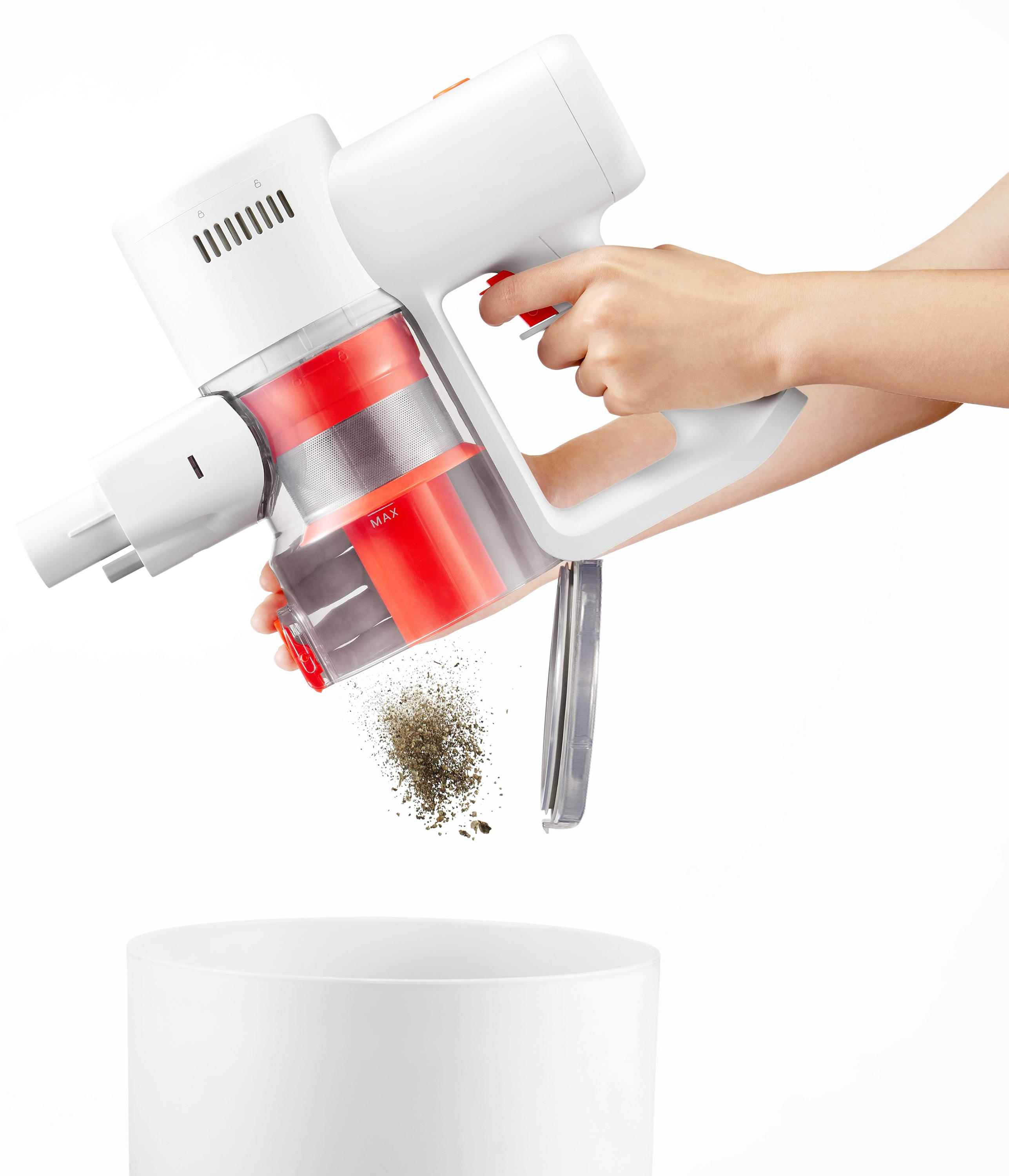 Ręka opróżnia zanieczyszczenia z białego odkurzacza bezprzewodowego do białego pojemnika.