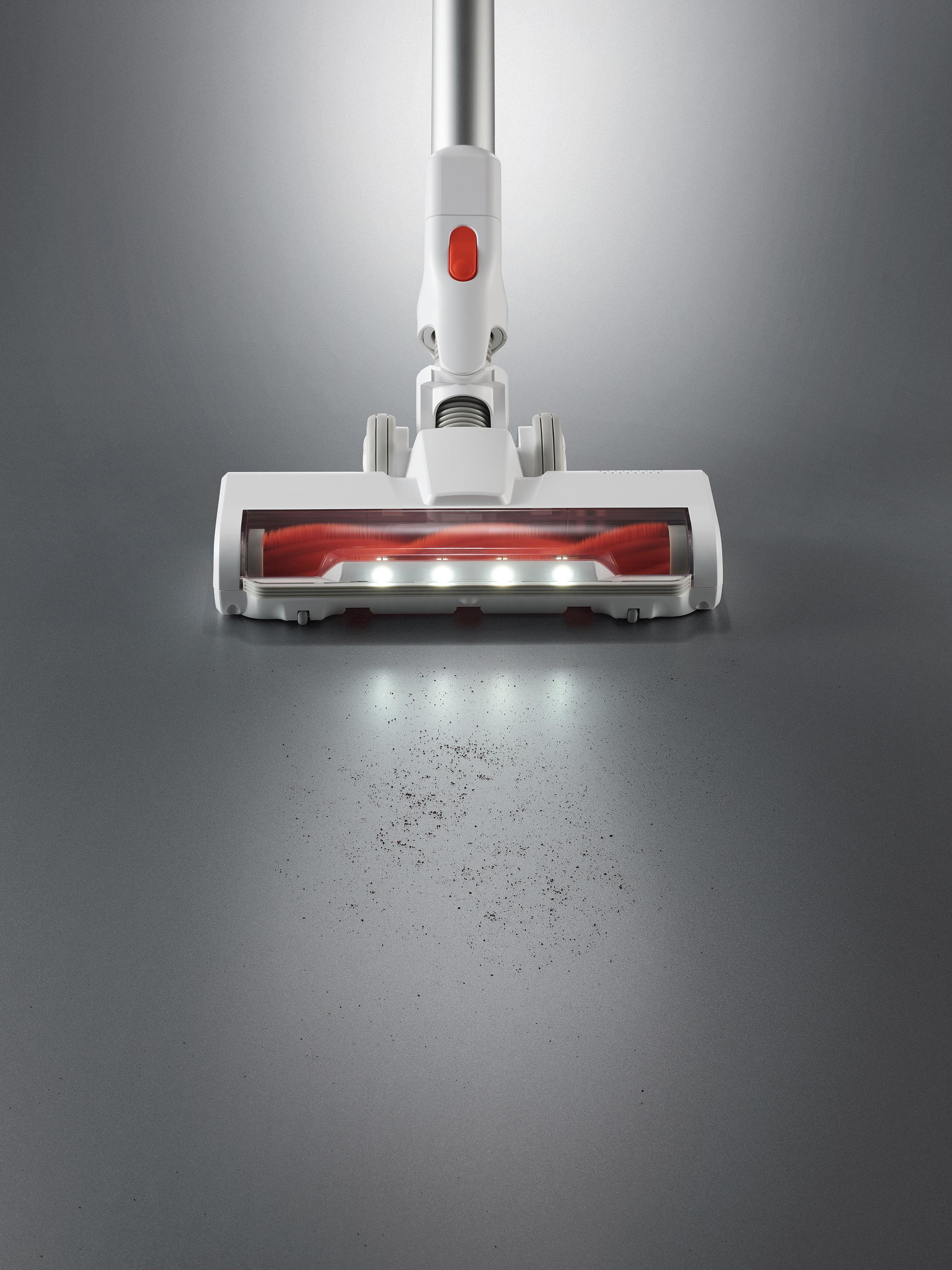 Biała głowica odkurzacza ze światłami, na szarej powierzchni. Ciemne plamy poniżej.